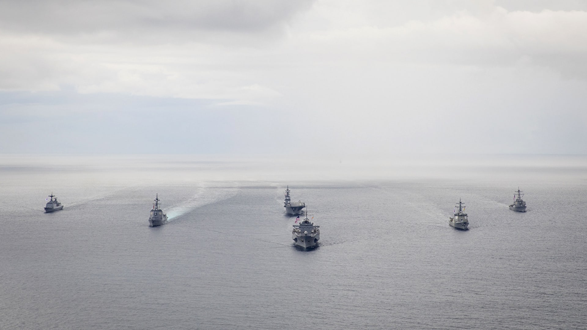 Several U.S. naval vessels cruising on open water.