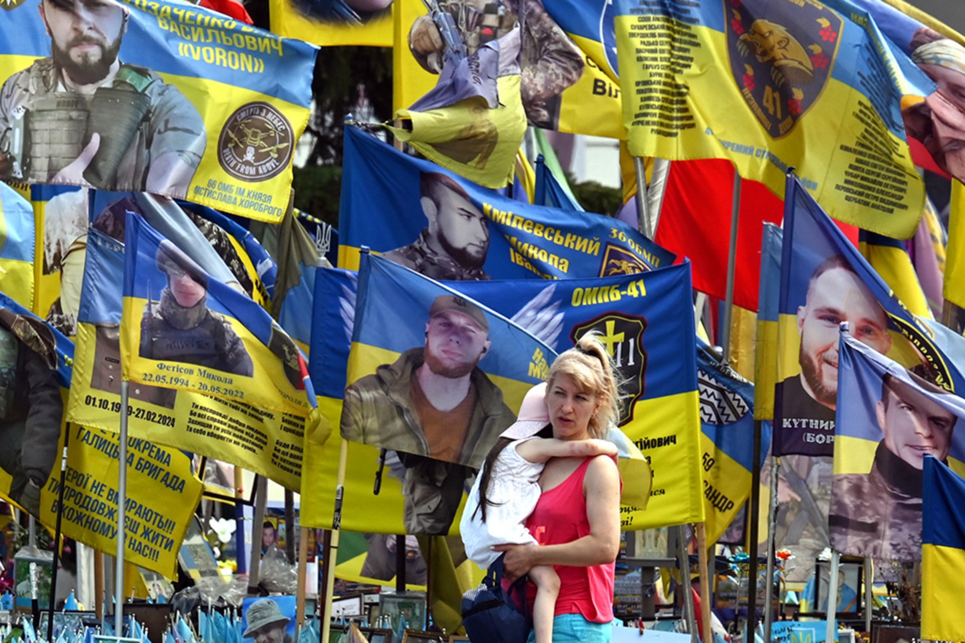 <p>A woman carrying a child walks at a memorial for fallen soldiers in Kyiv on August 4, 2025, amid the Russian invasion of Ukraine. </p>