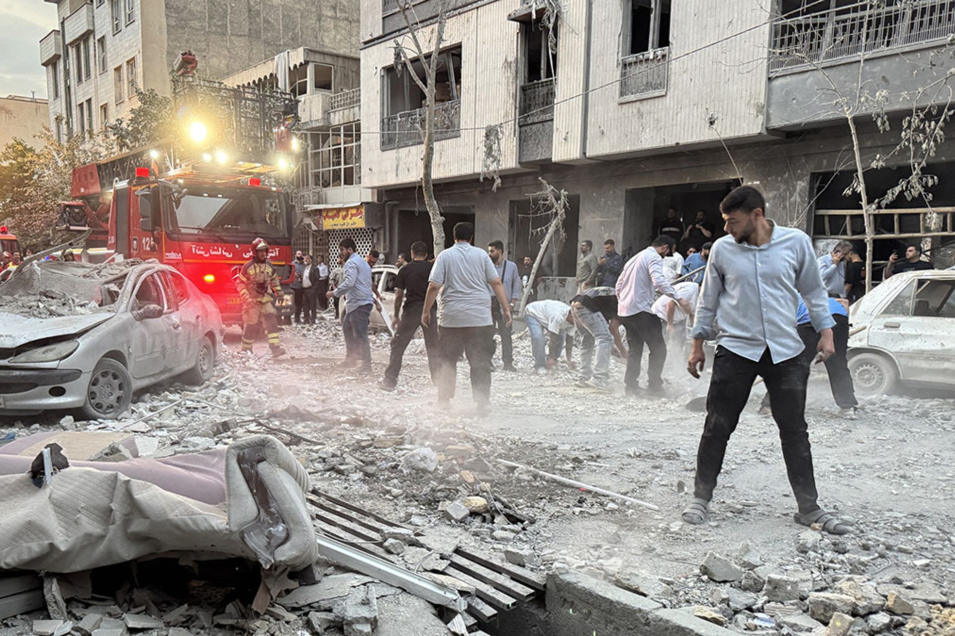 <p>People and first-responders gather outside a building that was hit by an Israeli strike in Tehran on June 13, 2025.</p>
