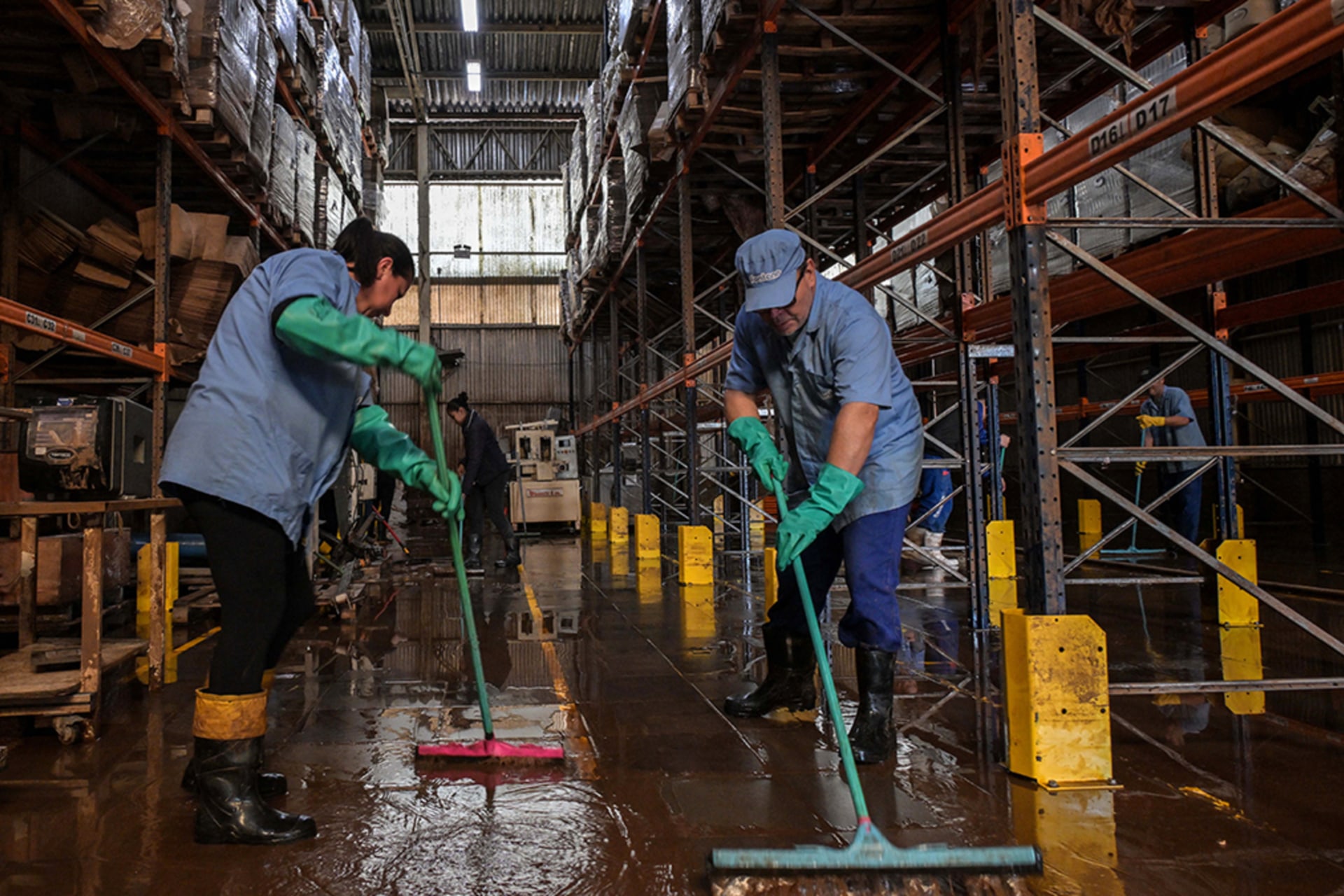 <p>Workers remove mud accumulated by flooding at an industrial plant in Rio Grande do Sul, Brazil.</p>