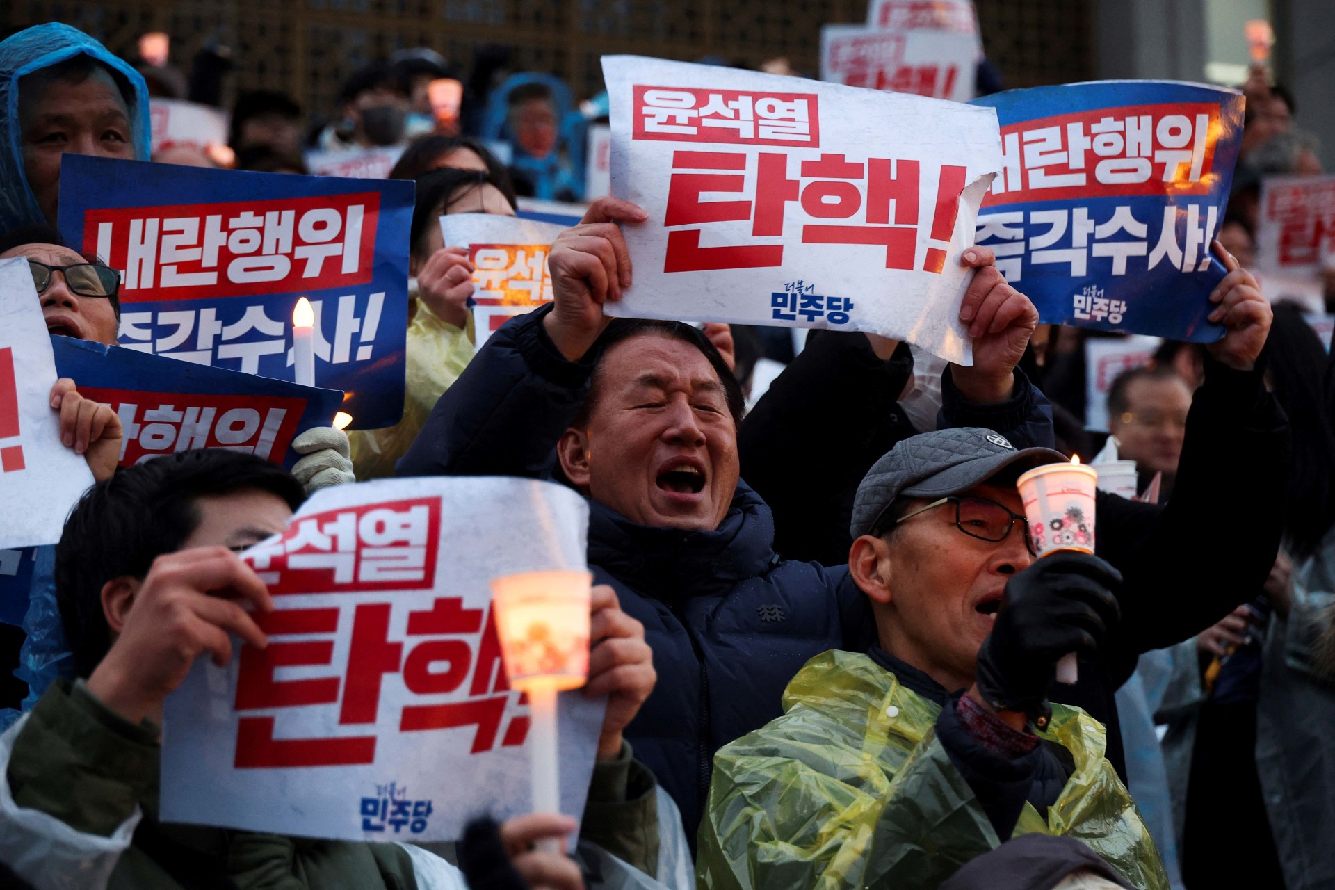 <p>People hold candles and signs during a candlelight vigil to demand the resignation of South Korean President Yoon Suk Yeol, who declared martial law which was reversed hours later, at the National Assembly in Seoul, South Korea</p>