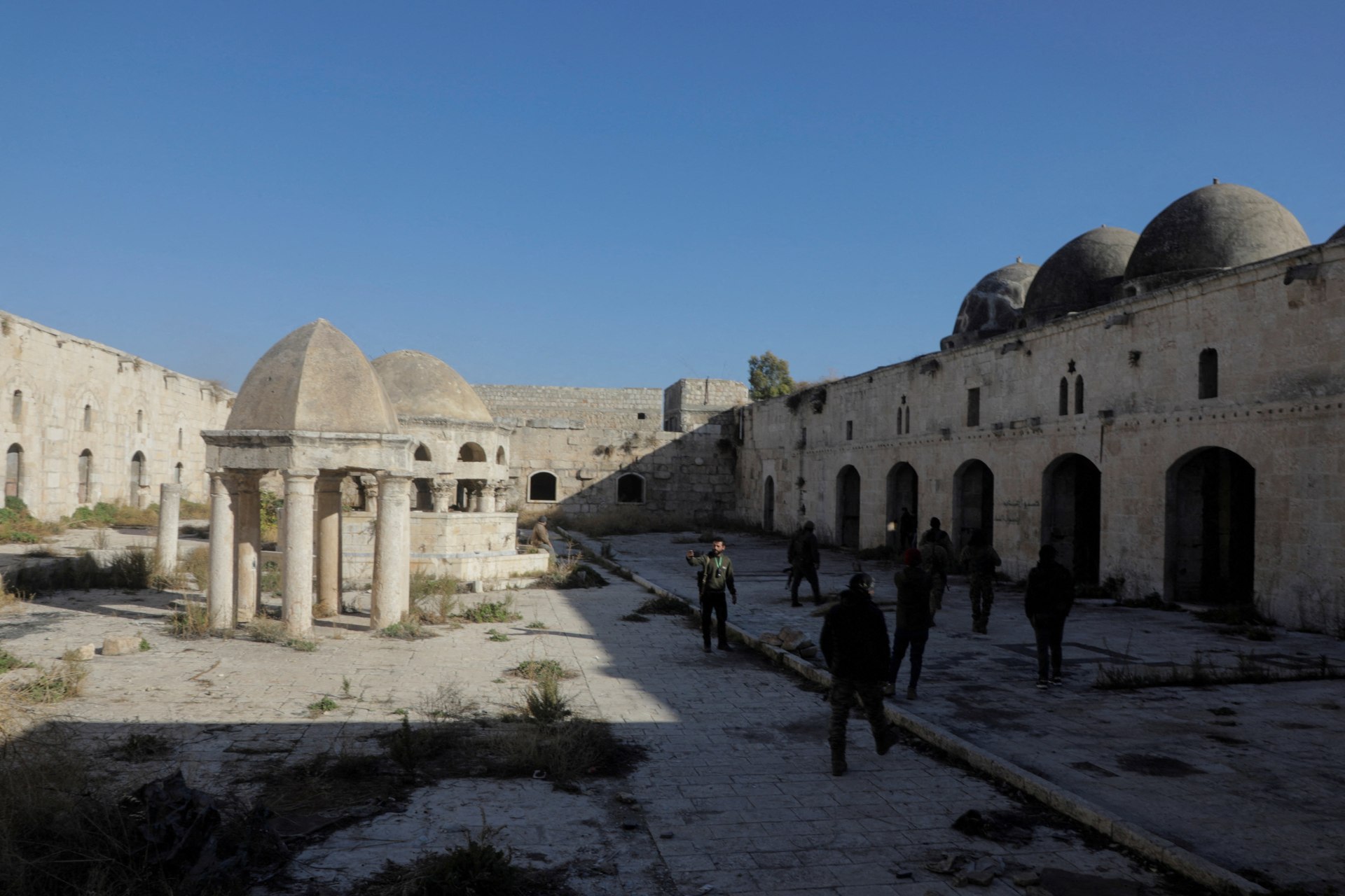 <p>Rebel fighters walk at the Great Mosque in the city of Maraat al-Numan in Idlib province on December 1, 2024.</p>