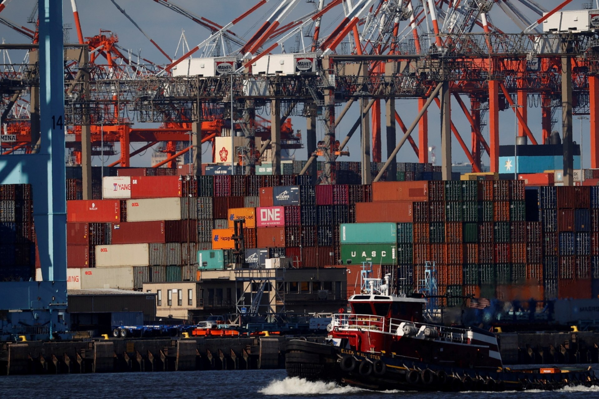 <p>A tugboat passes shipping containers being unloaded on a pier at Port Newark, New Jersey. </p>

