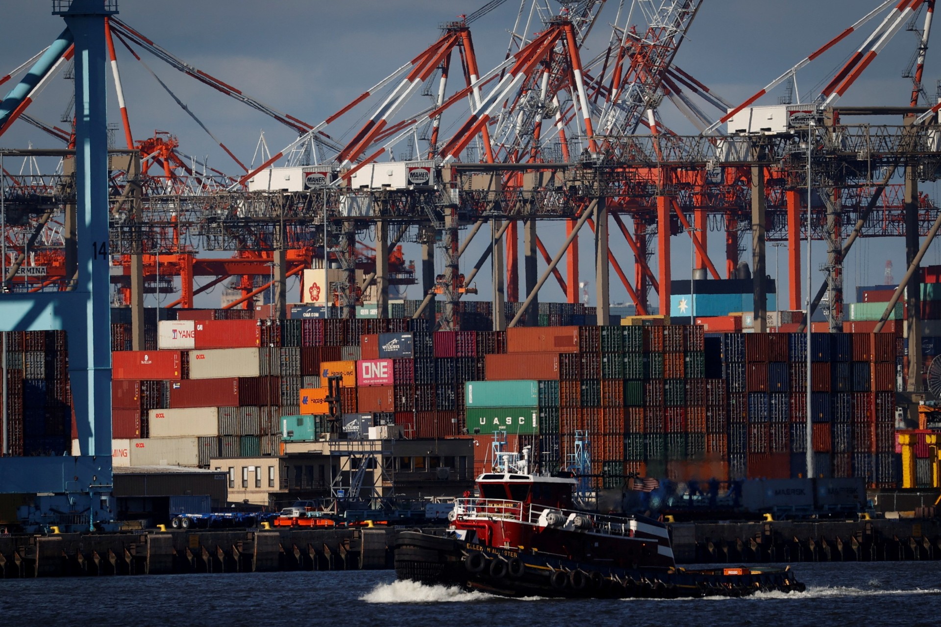 <p>A tugboat passes shipping containers being unloaded and stacked on a pier at Port Newark, New Jersey, U.S., November 19, 2021.</p>

