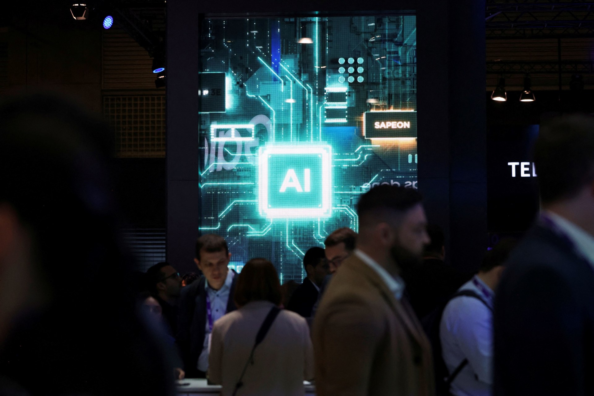 <p>People walk near a sign for Sapeon, an artificial intelligence (AI) chip company, at the Mobile World Congress (MWC) in Barcelona, Spain on February 27, 2024.</p>