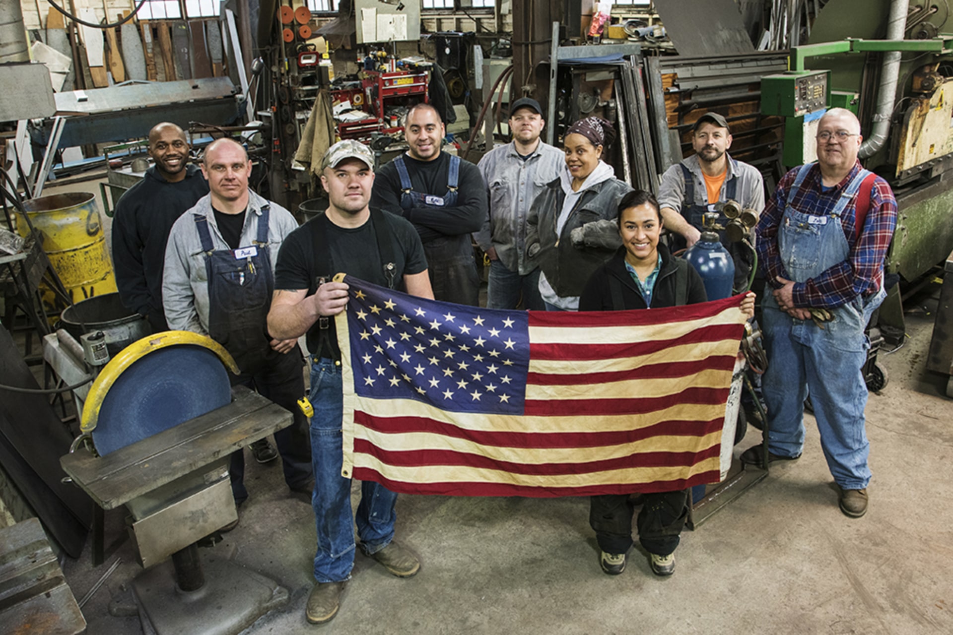 <p>High angle view of workers holding American flag in factory.</p>