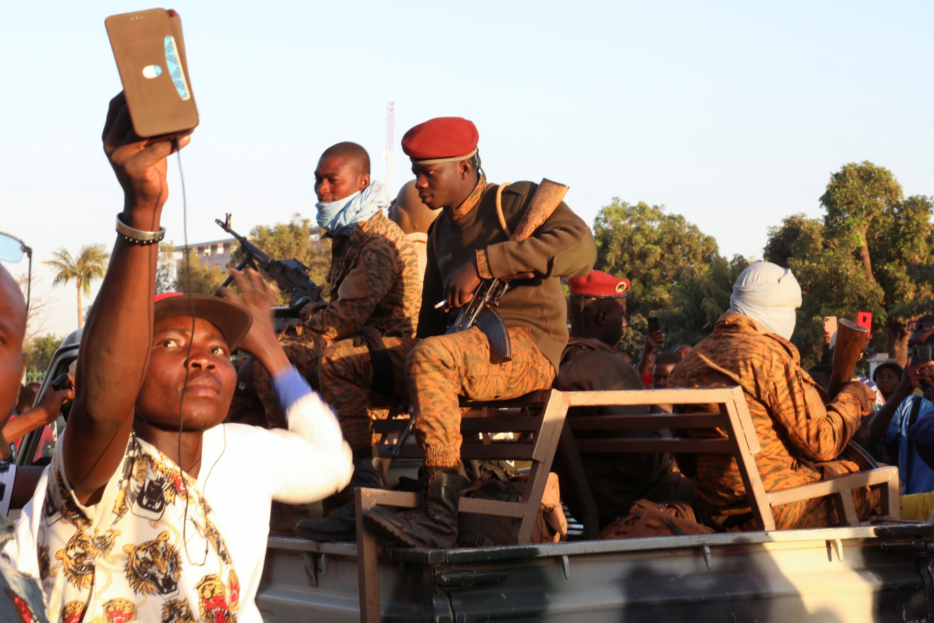 <p>A man uses his mobile phone beside army soldiers after they deposed President Kabore in Ouagadougou, Burkina Faso on January 24, 2022. </p>