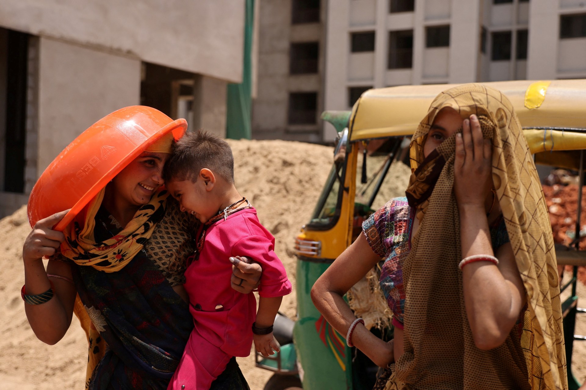 <p>Women take shelter from the sun at a construction site in Ahmedabad, India, April 28, 2023.</p>
