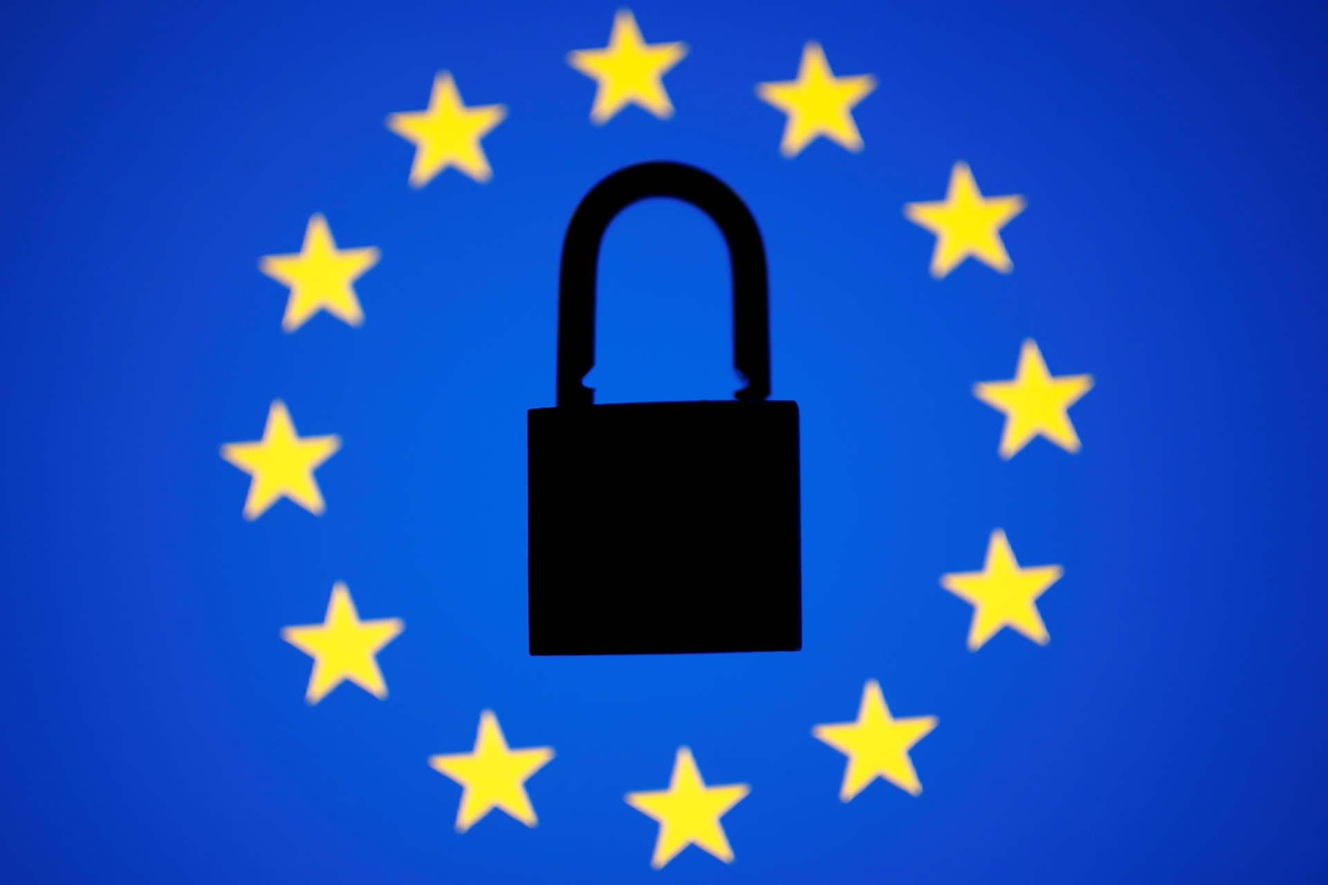 <p>A padlock sits in the center of a European Union flag.</p>
