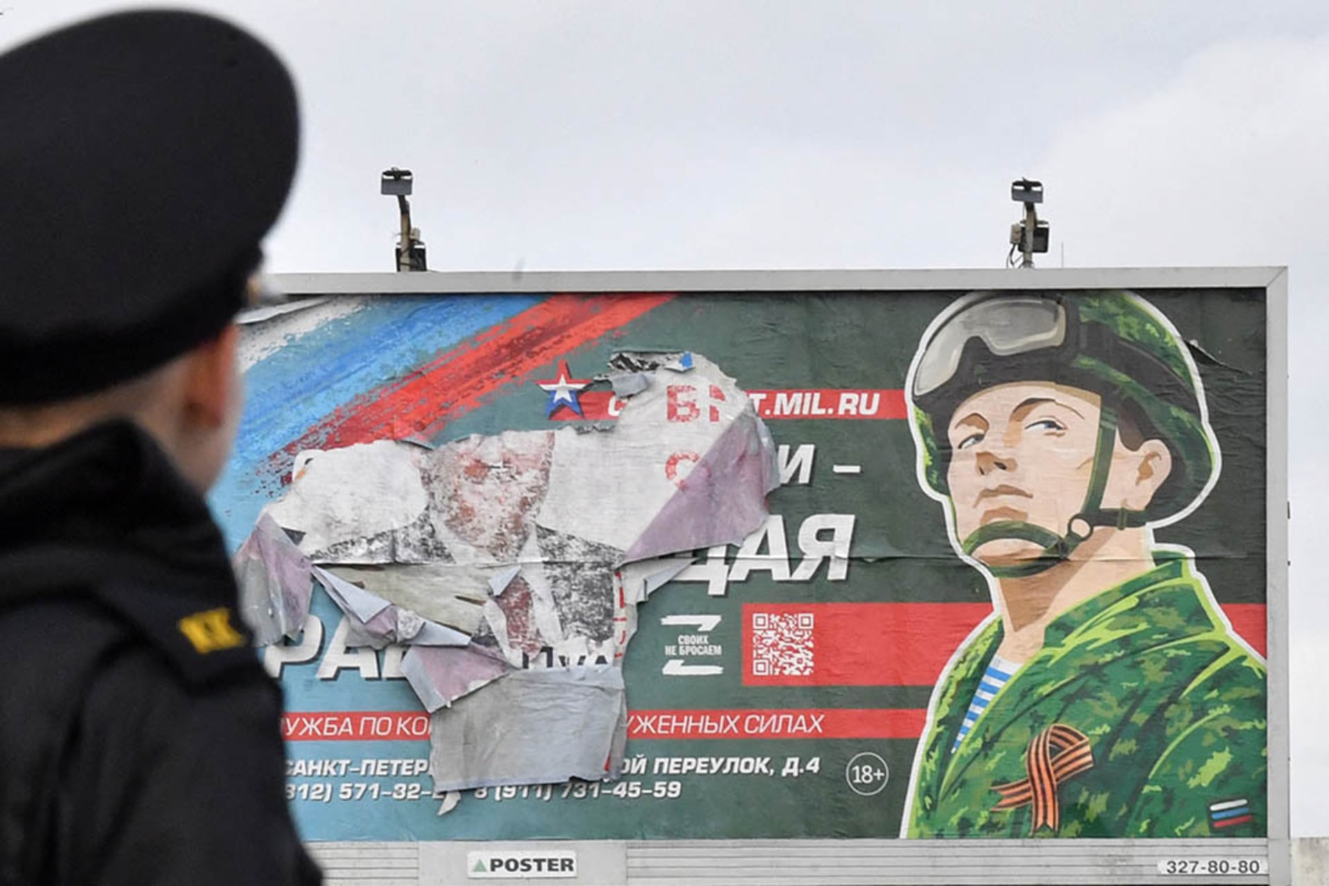<p>A Russian military cadet stands in front of a billboard promoting contract army service in St. Petersburg.</p>
