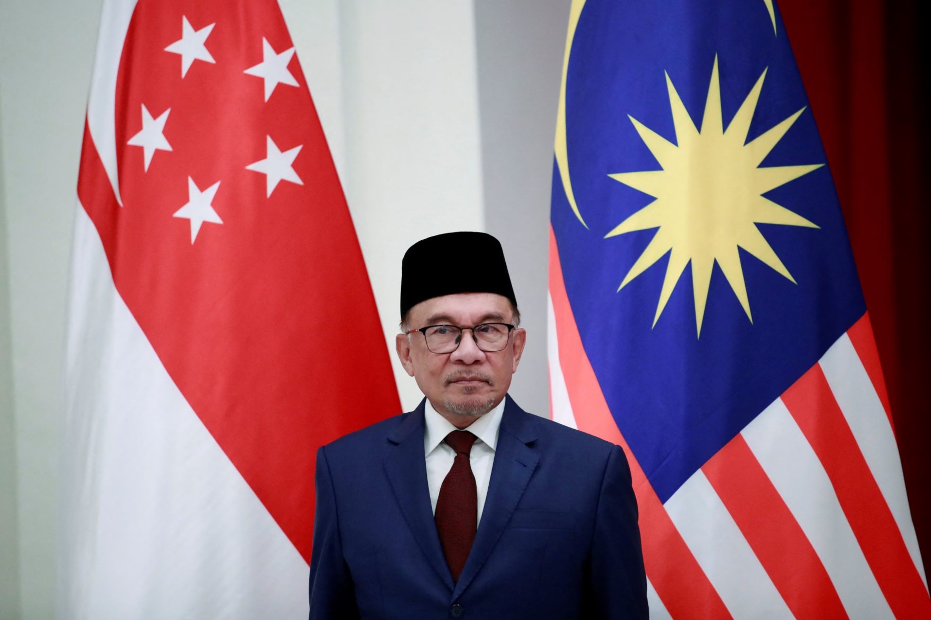 <p>Malaysian Prime Minister Anwar Ibrahim stands in front of the Singapore and Malaysian national flags during a signing ceremony at the Istana, or Presidential Palace in Singapore, on January 30, 2023. </p>