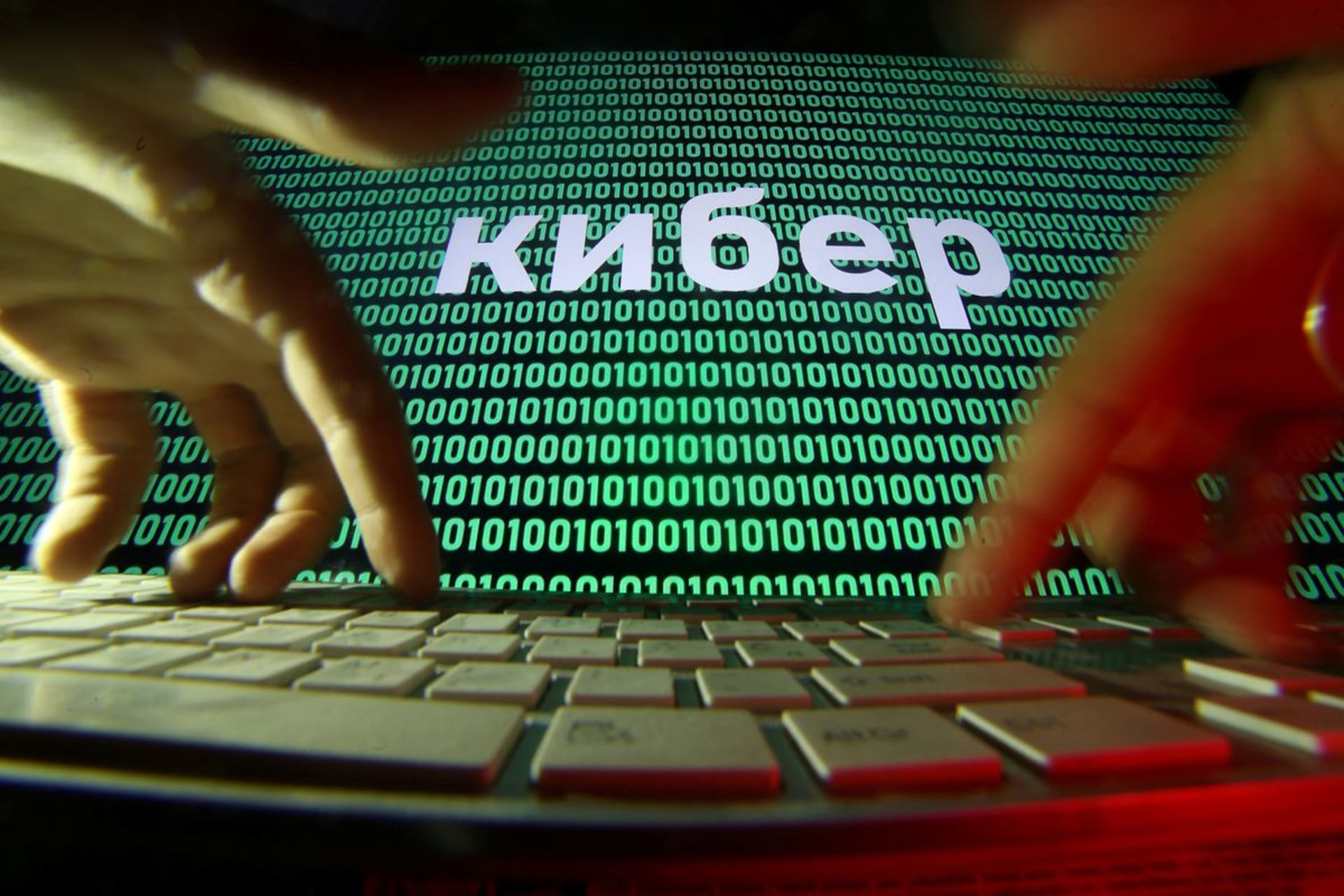 <p>A person types as a line of text in Russian appears superimposed over a screen of computer code.</p>
