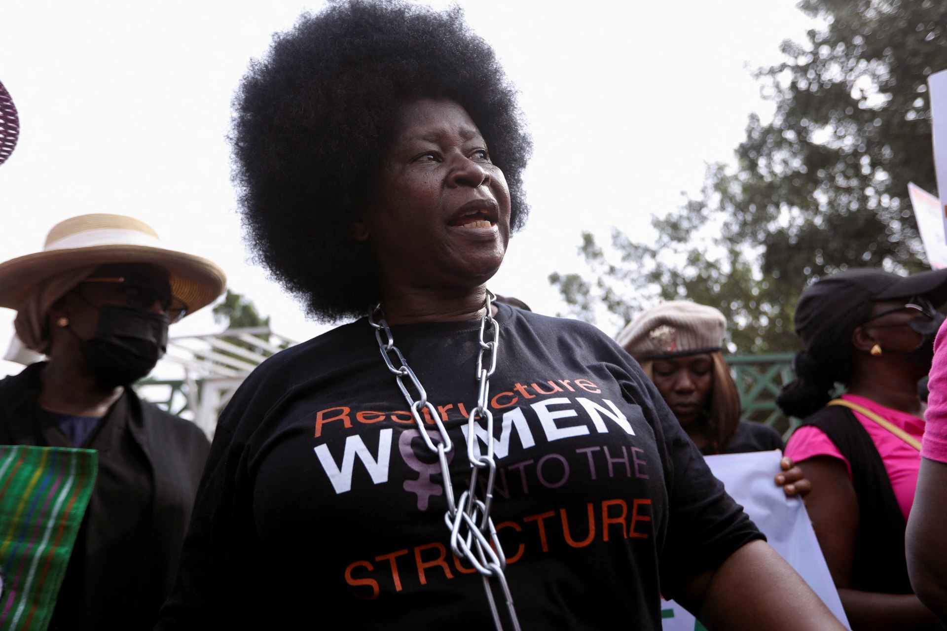 <p>A woman wearing chains around her neck marches during a protest against legislative bias against women on International Women’s Day in Abuja, Nigeria on March 8, 2022. The protest has been followed by a lockdown of the National Assembly Complex</p>