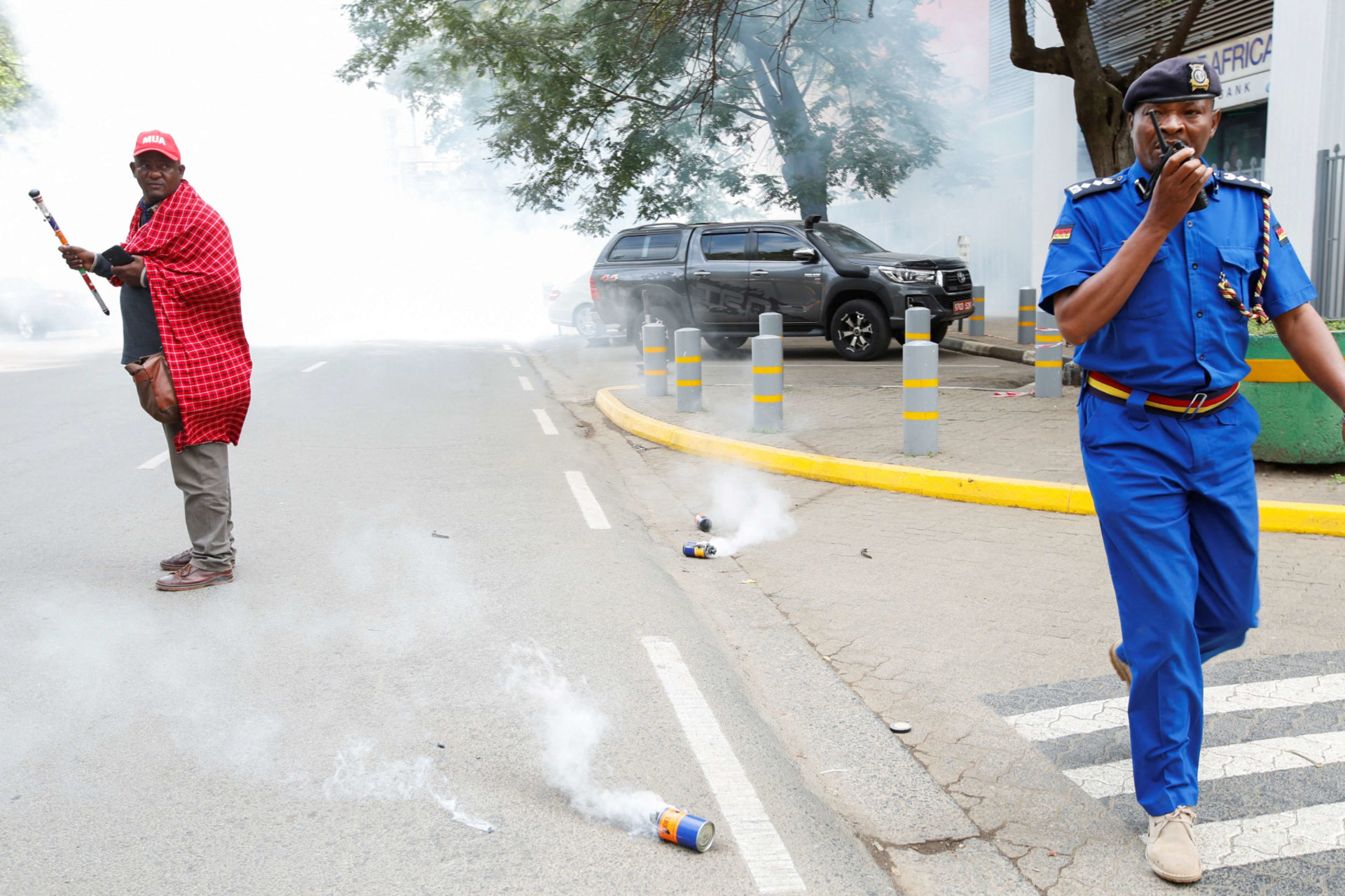 <p>A policeman calls for backup as Jonathan Mpute Ole Pasha, national coordinator of the Maa Unity Agenda (MUA) group in Kenya, stands amid tear gas during a Maasai protest against the eviction of their compatriots in Tanzania on June 17, 2022.</p>