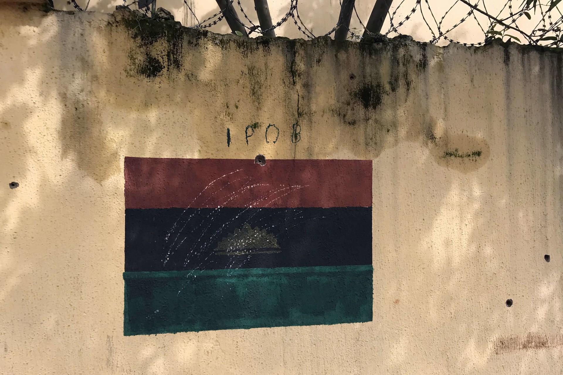 <p>A wall at the family home of Indigenous People of Biafra (IPOB) separatist leader Nnamdi Kanu depicts a painted flag of the former Republic of Biafra and holes purportedly caused by bullets in Umuahia, Nigeria on September 27, 2017.</p>
