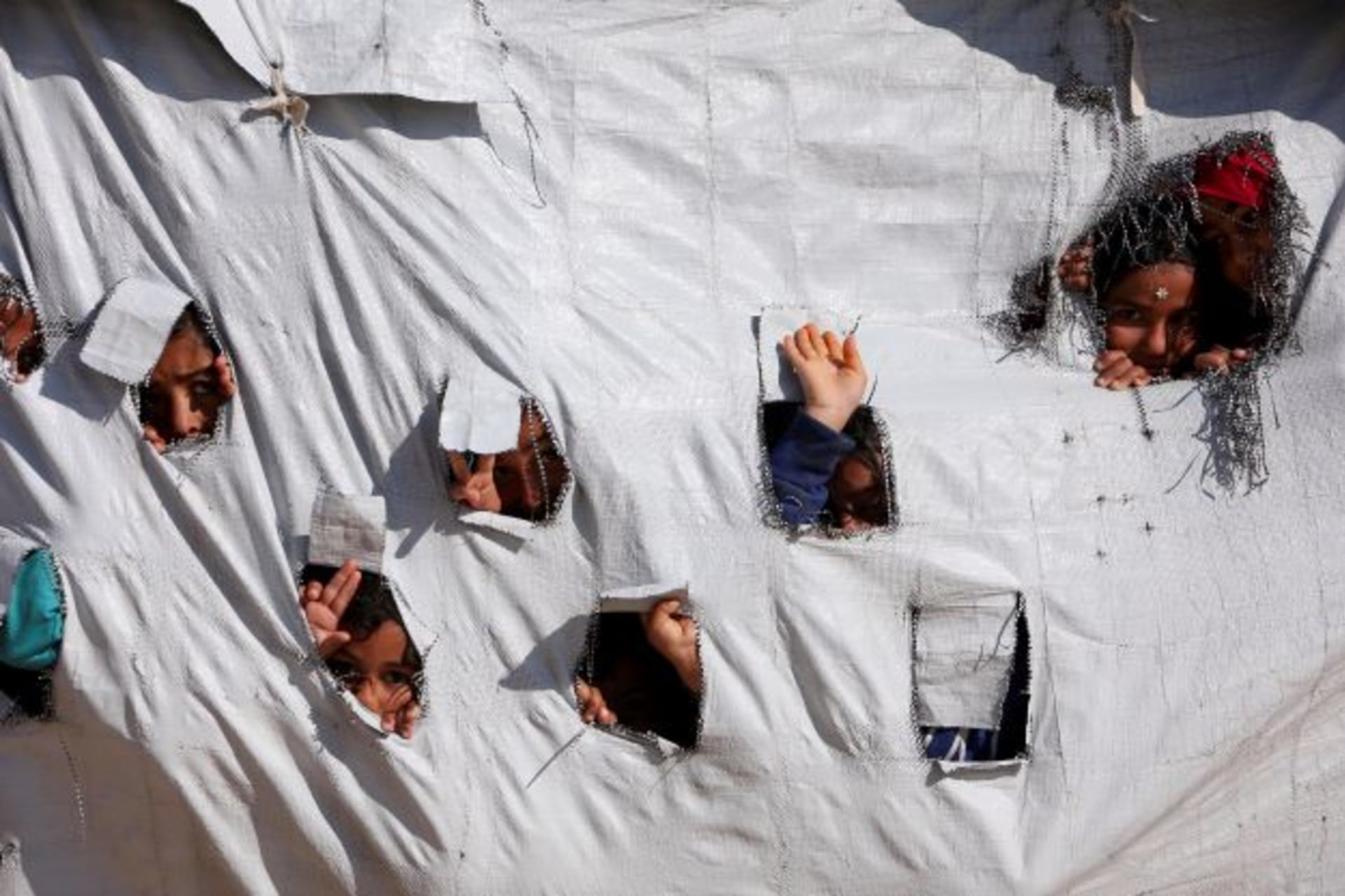 <p>Children look through holes in a tent at al Hol displacement camp in Hasaka governorate, Syria on April 2, 2019.</p>