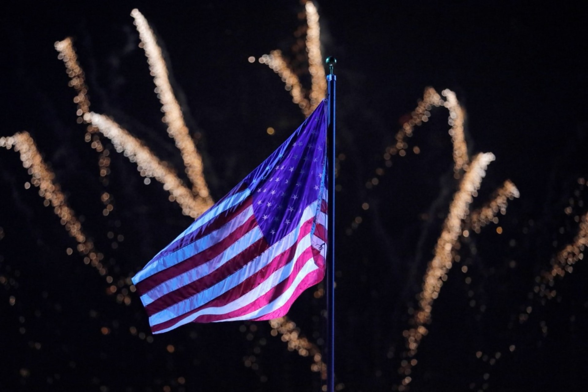 <p>Fireworks explode behind a U.S. flag during New York City’s Independence Day celebrations on July 4, 2021.</p>
