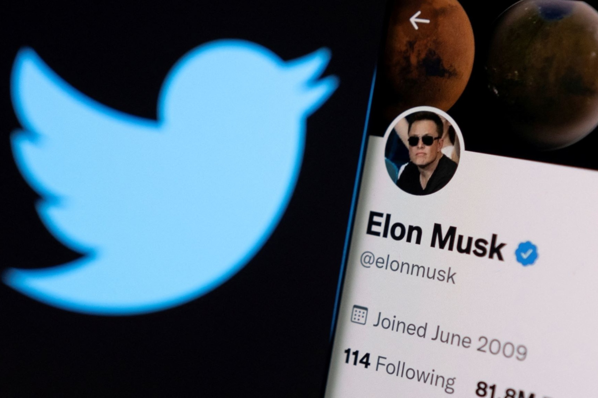 <p>Elon Musk’s twitter account is seen on a smartphone in front of the Twitter logo in this photo illustration taken on April 15, 2022. </p>