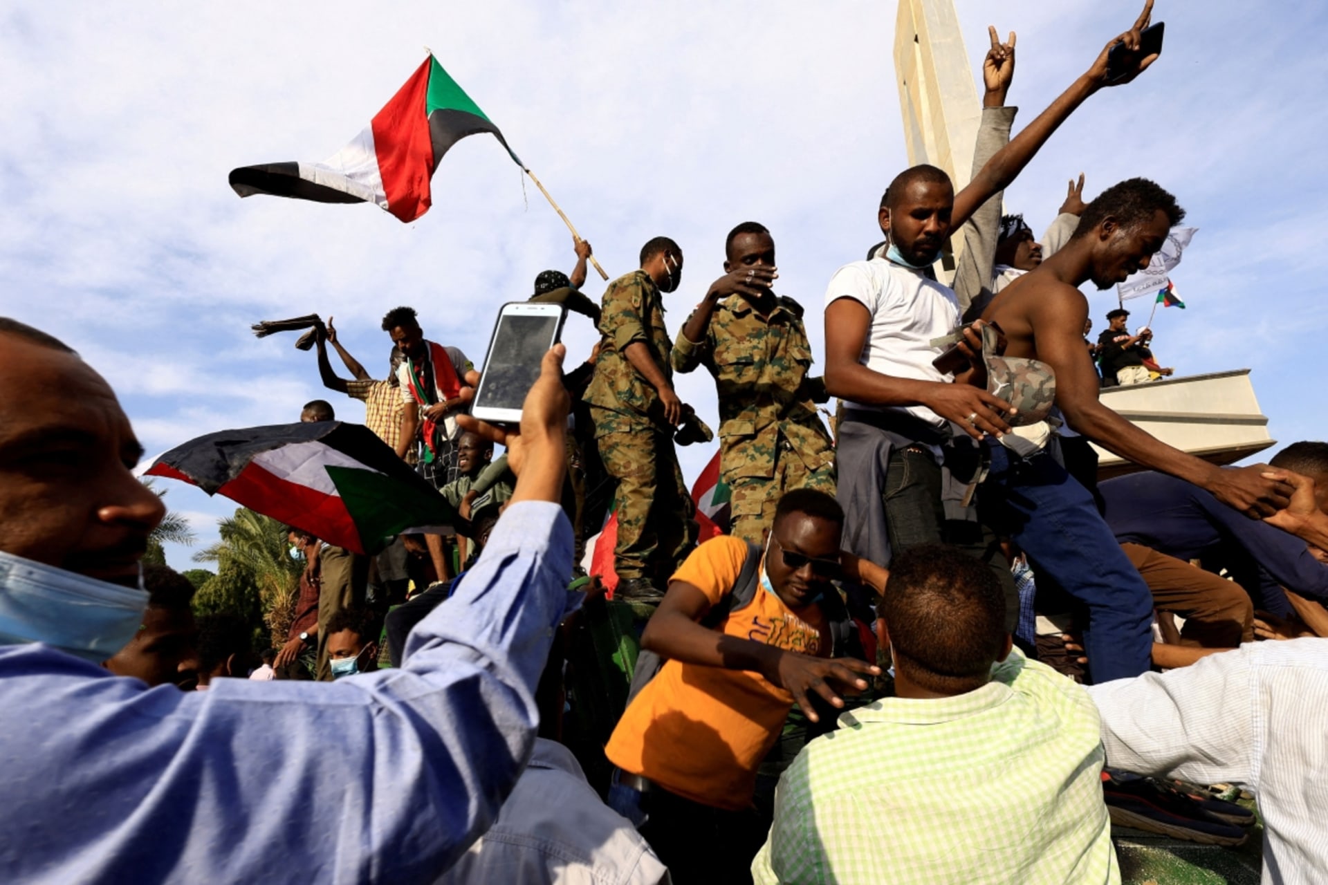 <p>People ride on top of military vehicle as they celebrate reaching the presidential palace protesting against military rule following last month’s coup in Khartoum, Sudan on December 19, 2021.</p>
