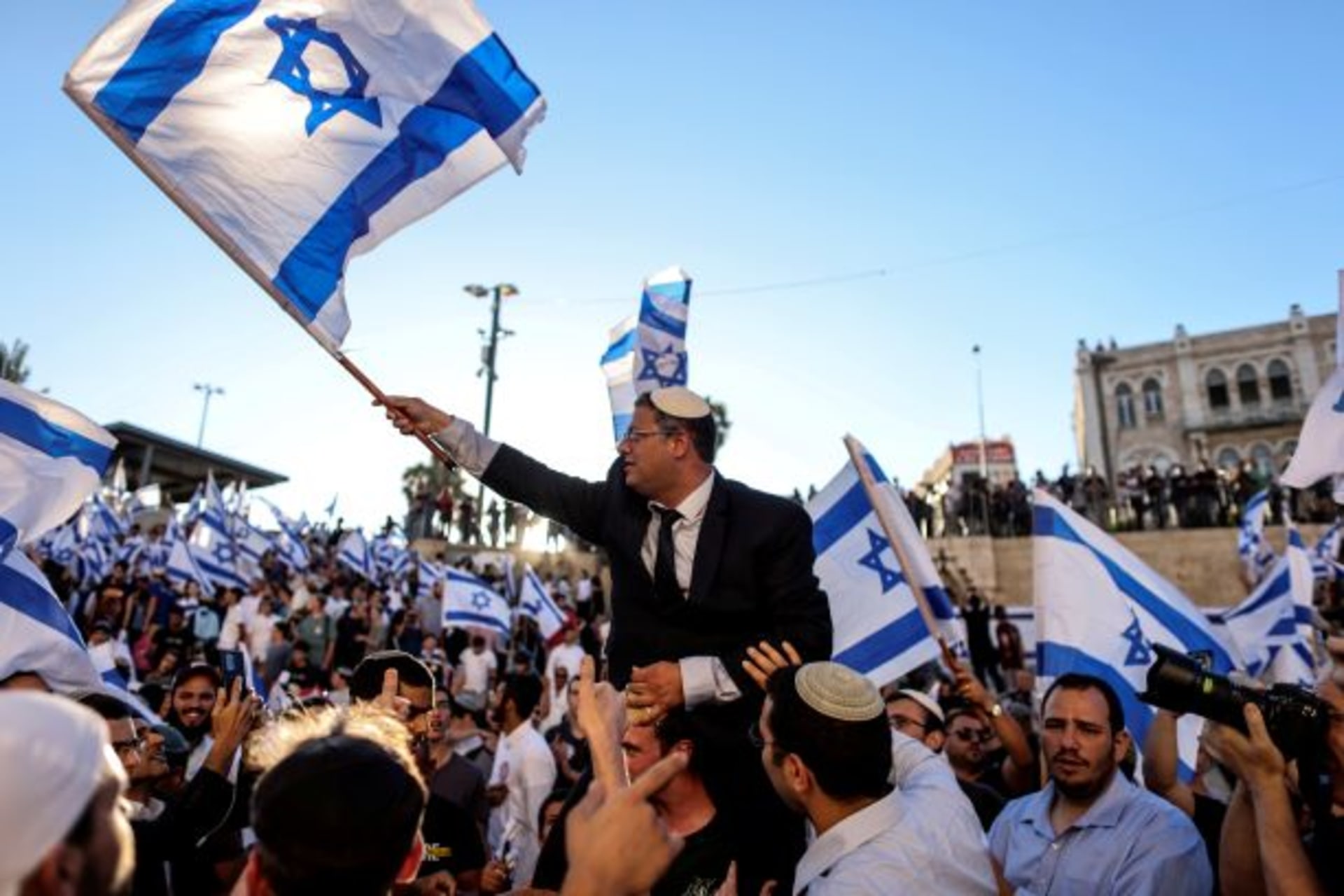 <p>Israeli lawmaker Itamar Ben Gvir carries an Israeli flag as he dances together with others by Damascus gate just outside Jerusalem’s Old City June 15, 2021.</p>