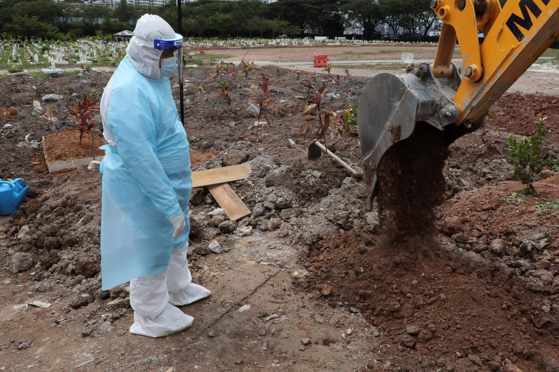 <p>A cemetery worker wearing a protective suit helps to bury a victim of the coronavirus disease (COVID-19) at a cemetery in Shah Alam, Malaysia, July 14, 2021.</p>