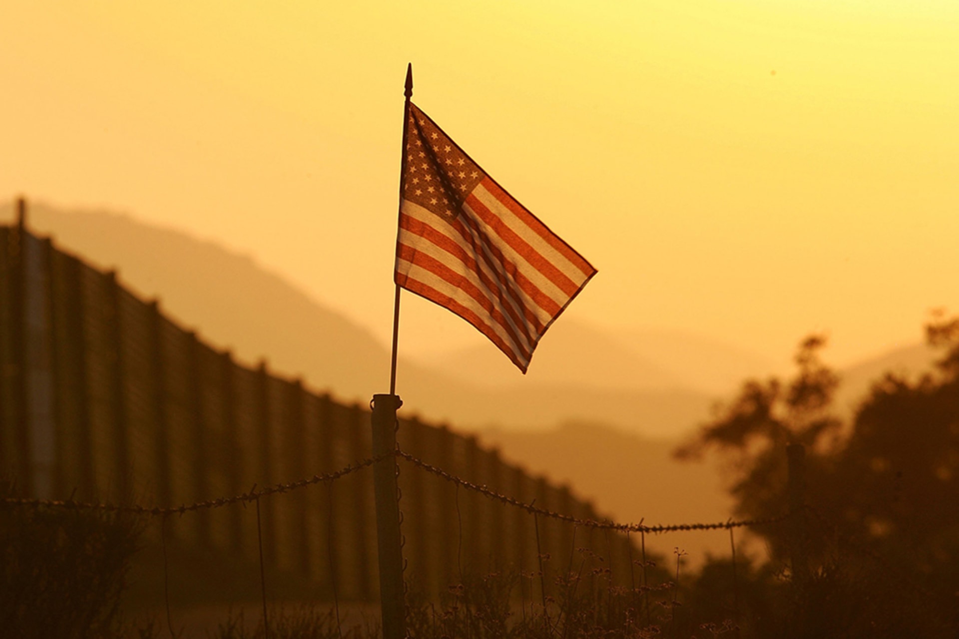 <p>A U.S. flag flies in front of the U.S.-Mexico border fence near Campo, California.</p>

