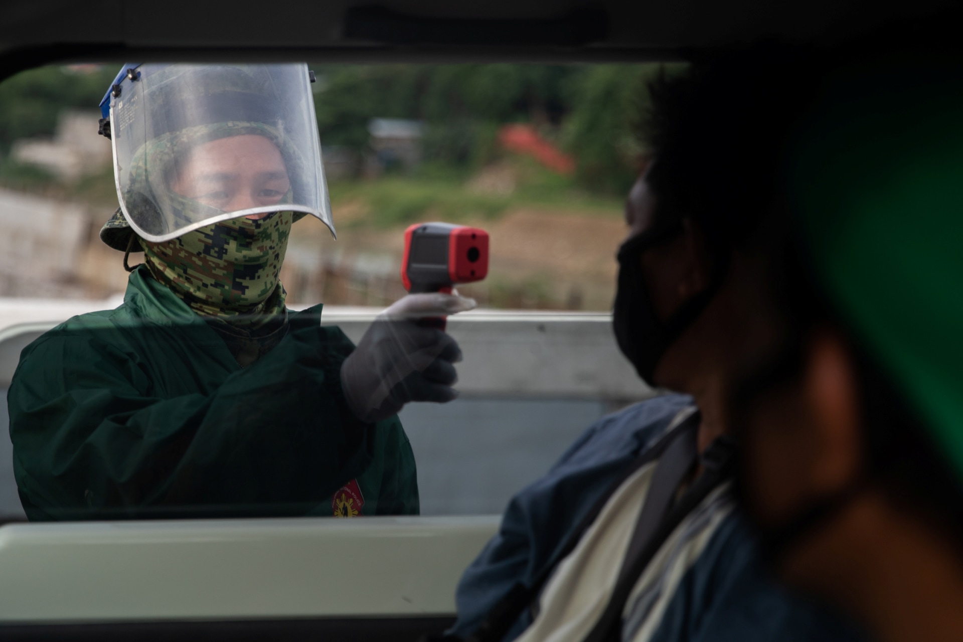 <p>A police officer checks a passenger’s body temperature at a quarantine checkpoint amid the reimposed strict lockdown to curb COVID-19 infections, in Quezon City, Metro Manila, Philippines, on August 5, 2020.</p>
