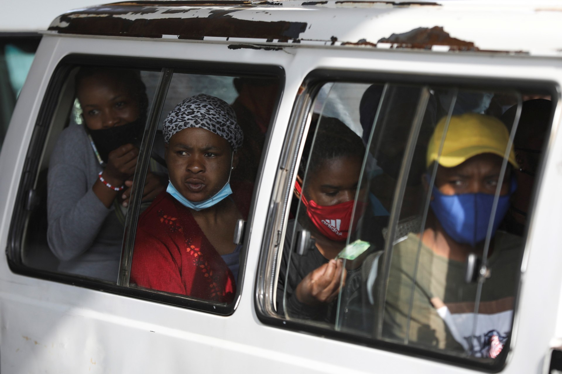 <p>Commuters, some wearing face masks, look on through a window at the Baragwanath taxi rank, amid the coronavirus disease (COVID-19) outbreak, in Soweto, South Africa on December 29, 2020.</p>