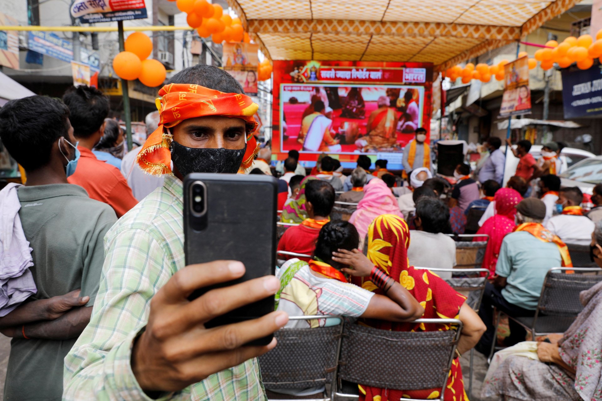 <p>A man takes a selfie during a live screening of a ceremony by Prime Minister Narendra Modi.</p>
