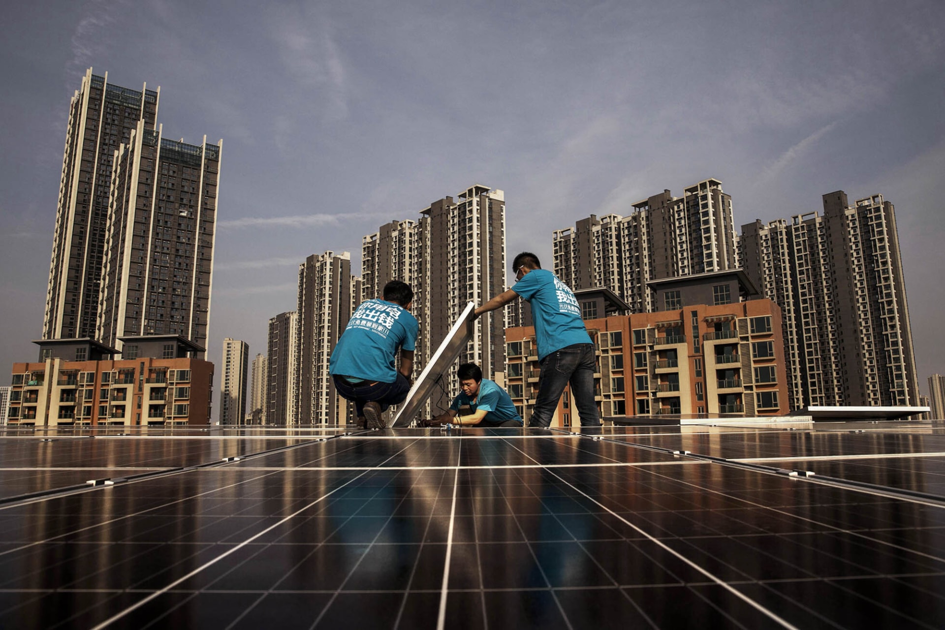 <p>Workers install solar panels on a building’s roof in China.</p>
