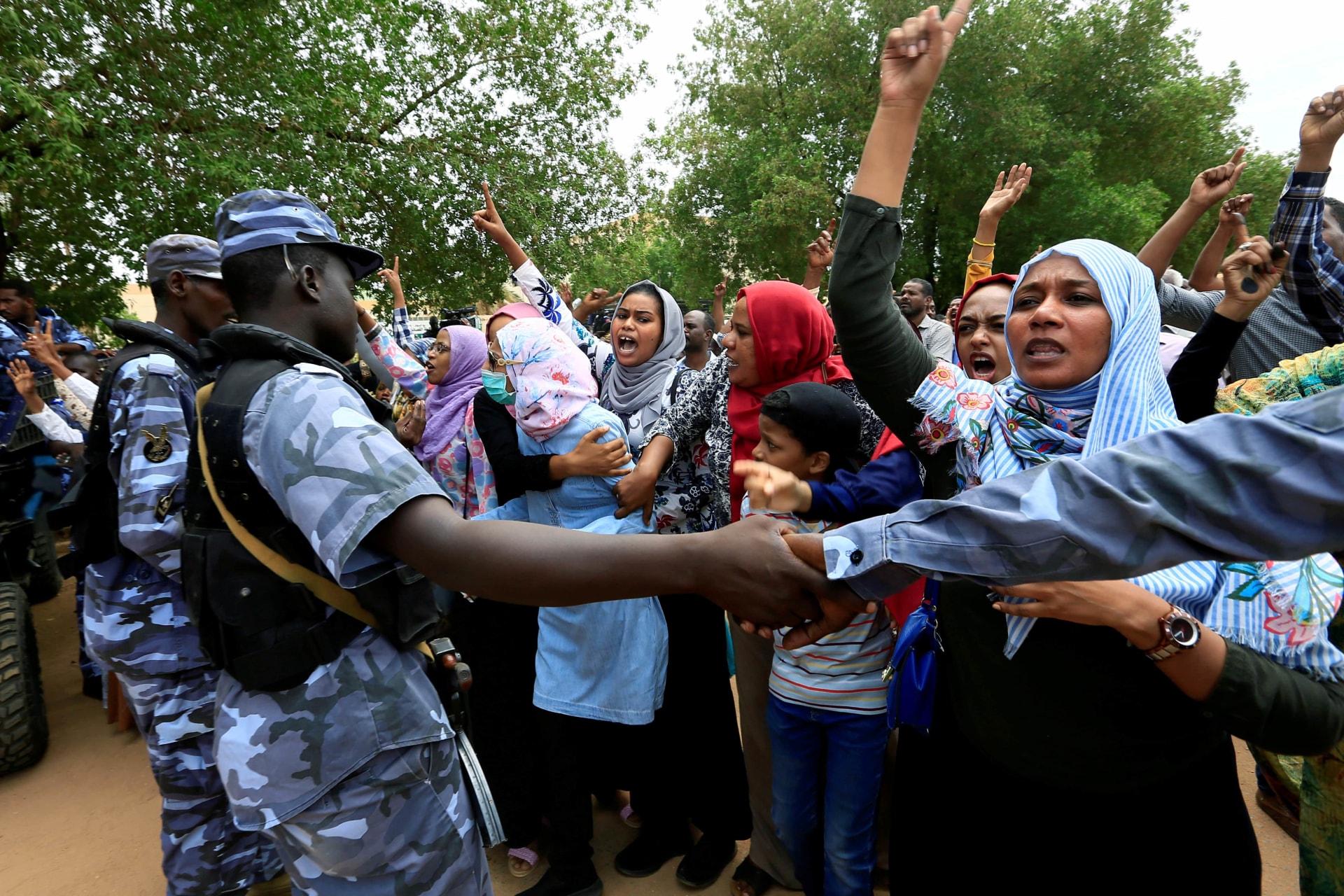 <p>Sudanese chant slogans outside a court during a new trial against ousted President Omar al-Bashir and some of his former allies over the military coup that brought the autocrat to power in 1989, outside a courthouse in Khartoum, Sudan. September 15, 2020</p>