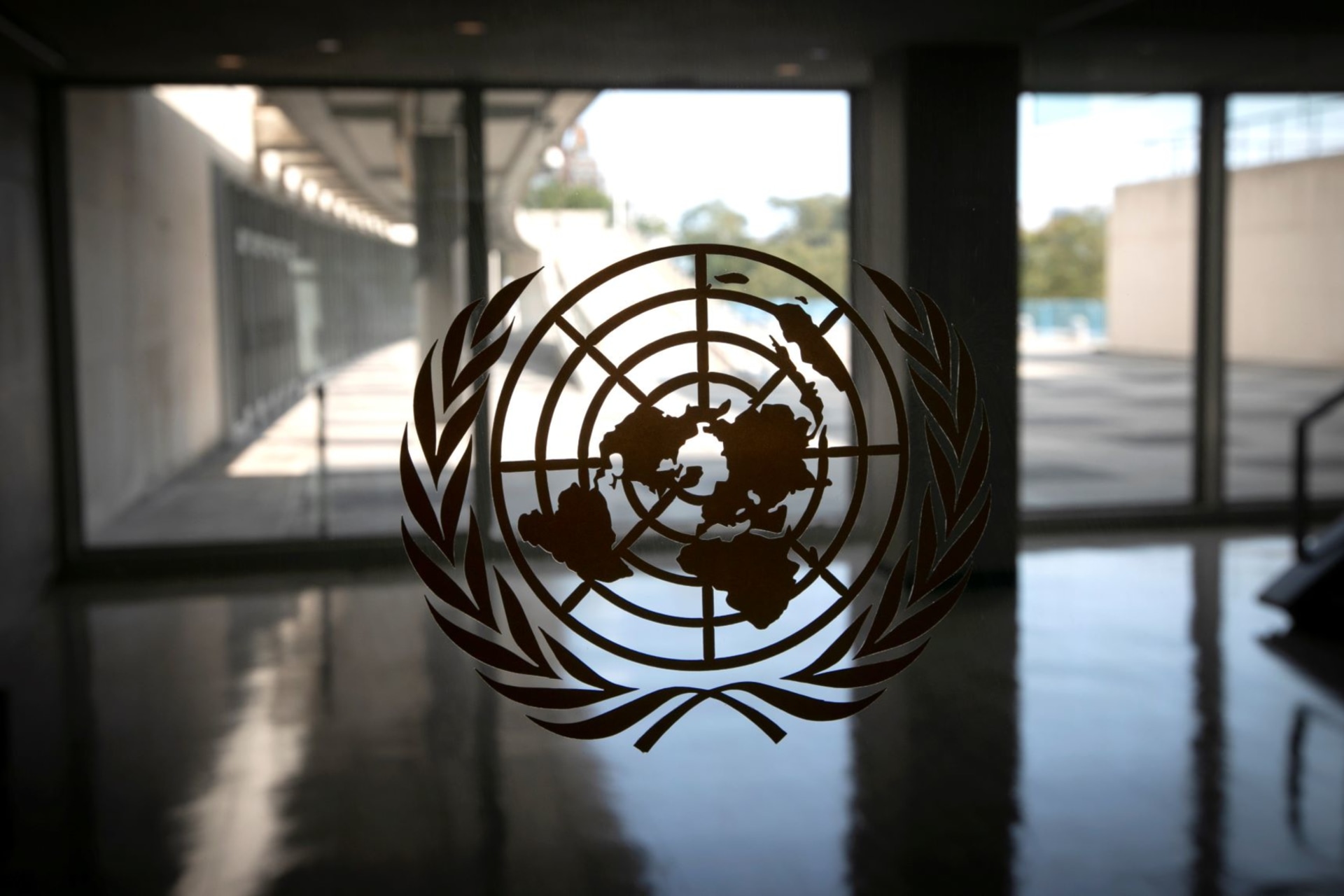 <p>The United Nations logo is seen on a window in an empty hallway at UN headquarters during the seventy-fifth annual UN General Assembly on September 21, 2020. </p>
