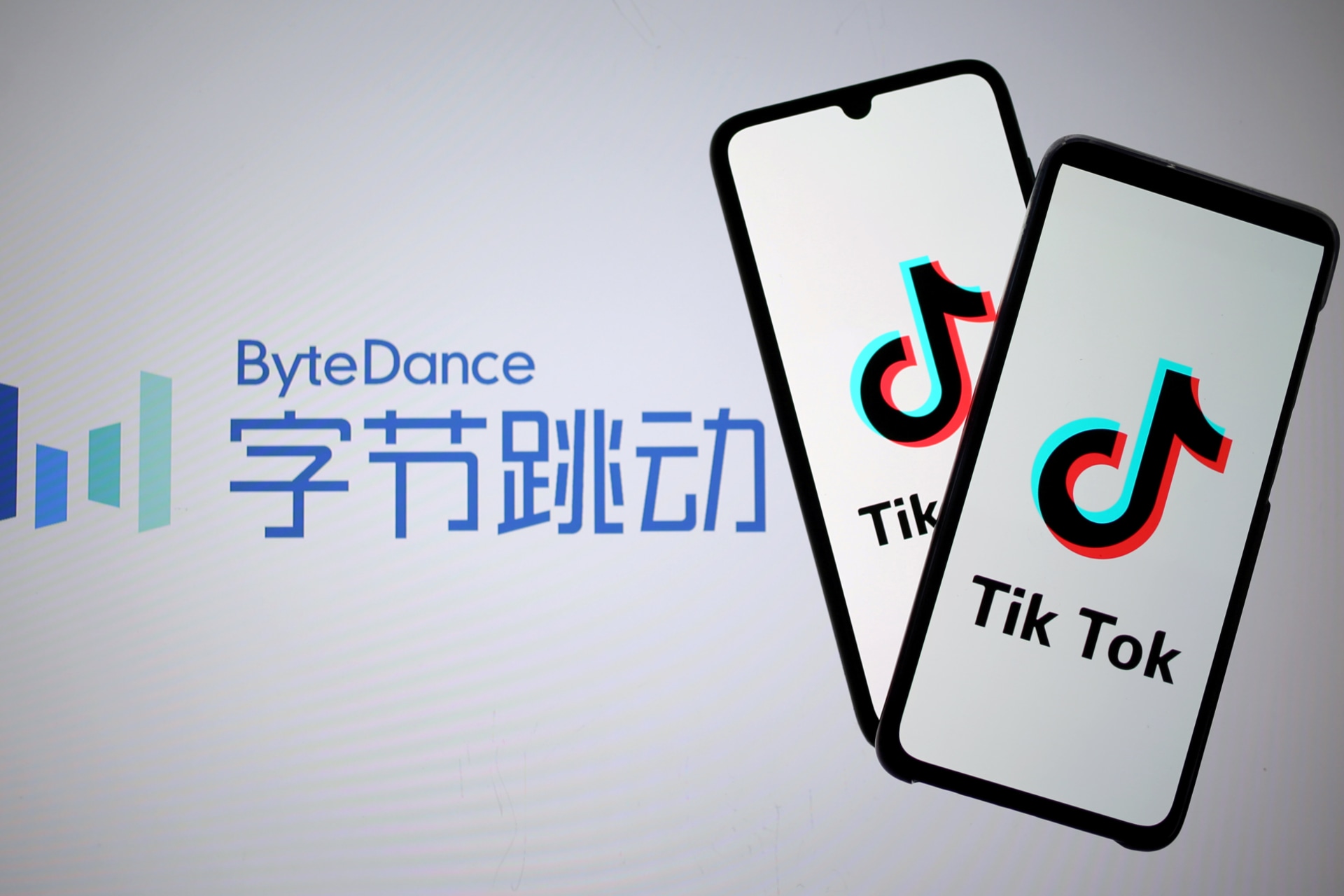 <p>TikTok logos are seen on smartphones in front of a displayed ByteDance logo.</p>