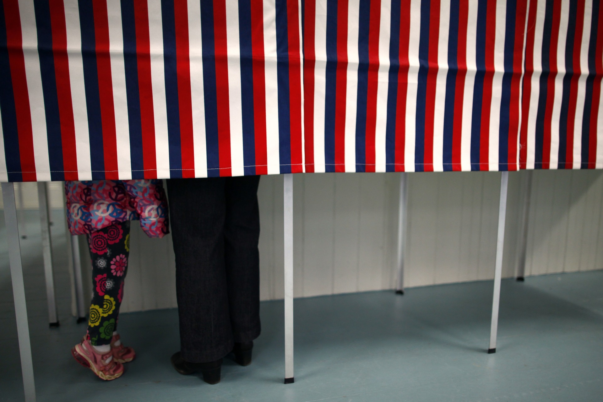 <p>A girl tiptoes as a woman votes in the primary election at Deerfield Town Hall in Deerfield, New Hampshire, United States. January 10, 2012.</p>

