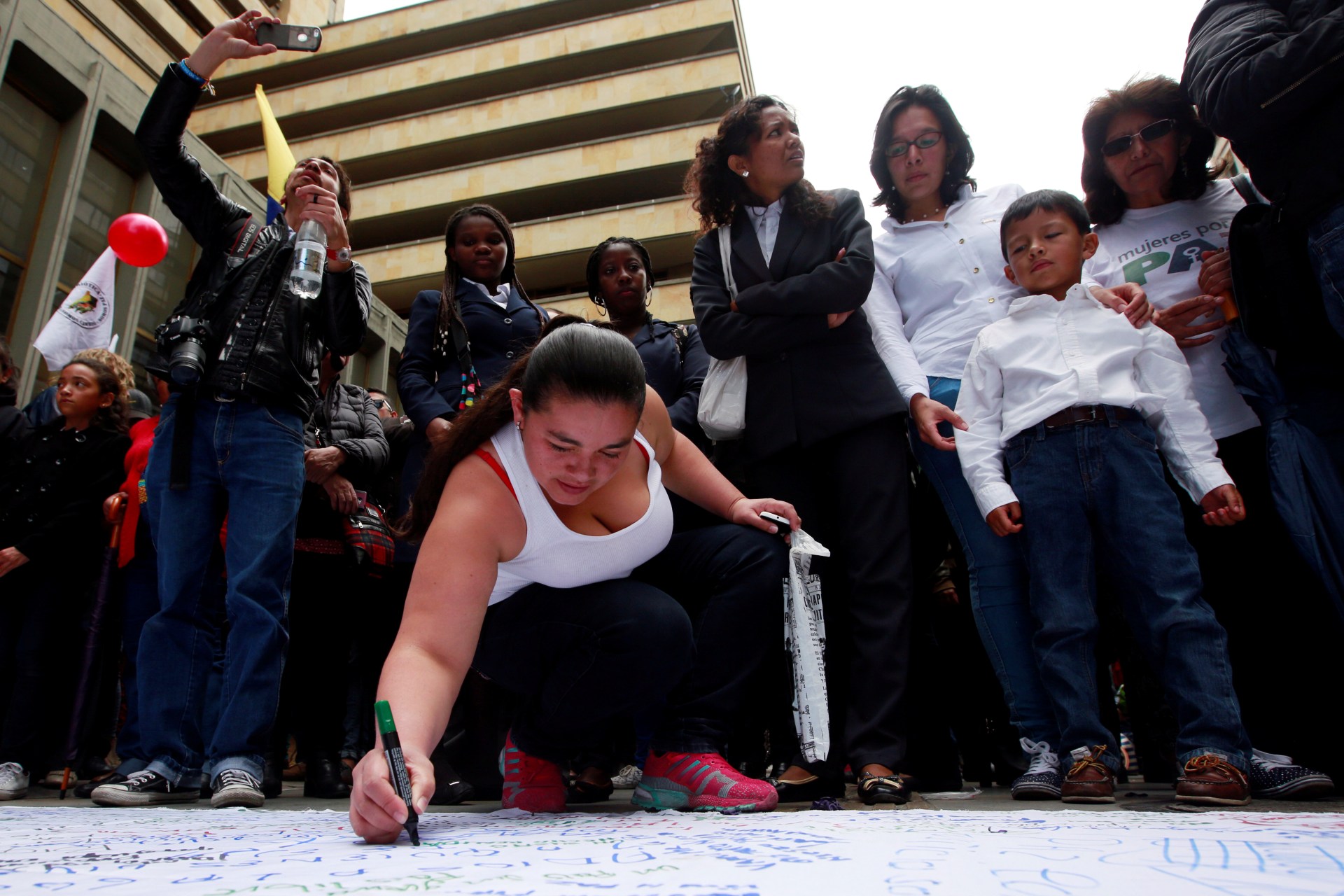 <p>A woman writes a message about peace on a banner as people celebrate the signing of a historic ceasefire deal between the Colombian government and FARC rebels in Bogota, Colombia, June 23, 2016. </p>