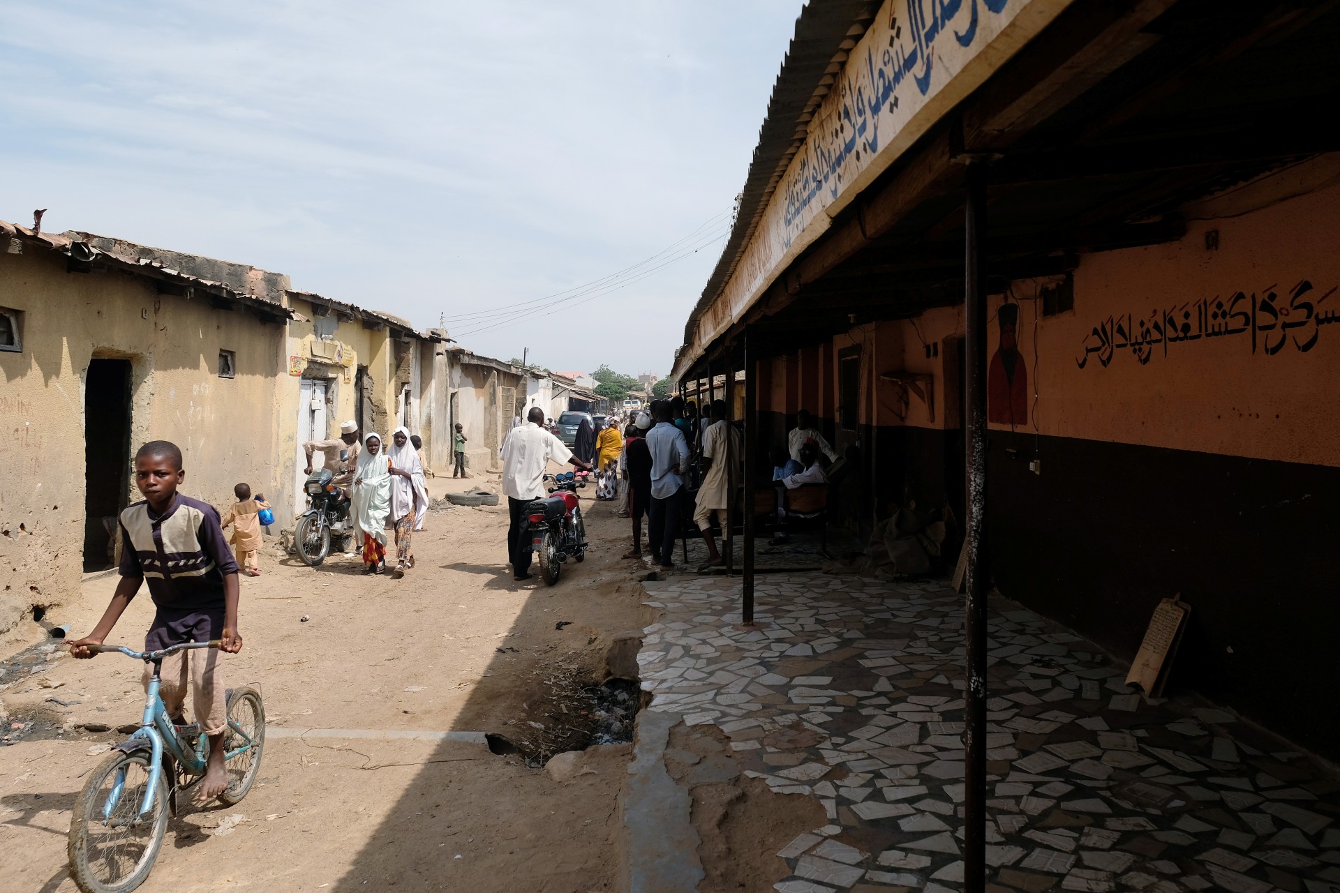 <p>People pass by the site of Mallam Nigas’s Islamic school and rehabilitation center, which was raided by police last week, in Katsina, Nigeria, on October 18, 2019.</p>
