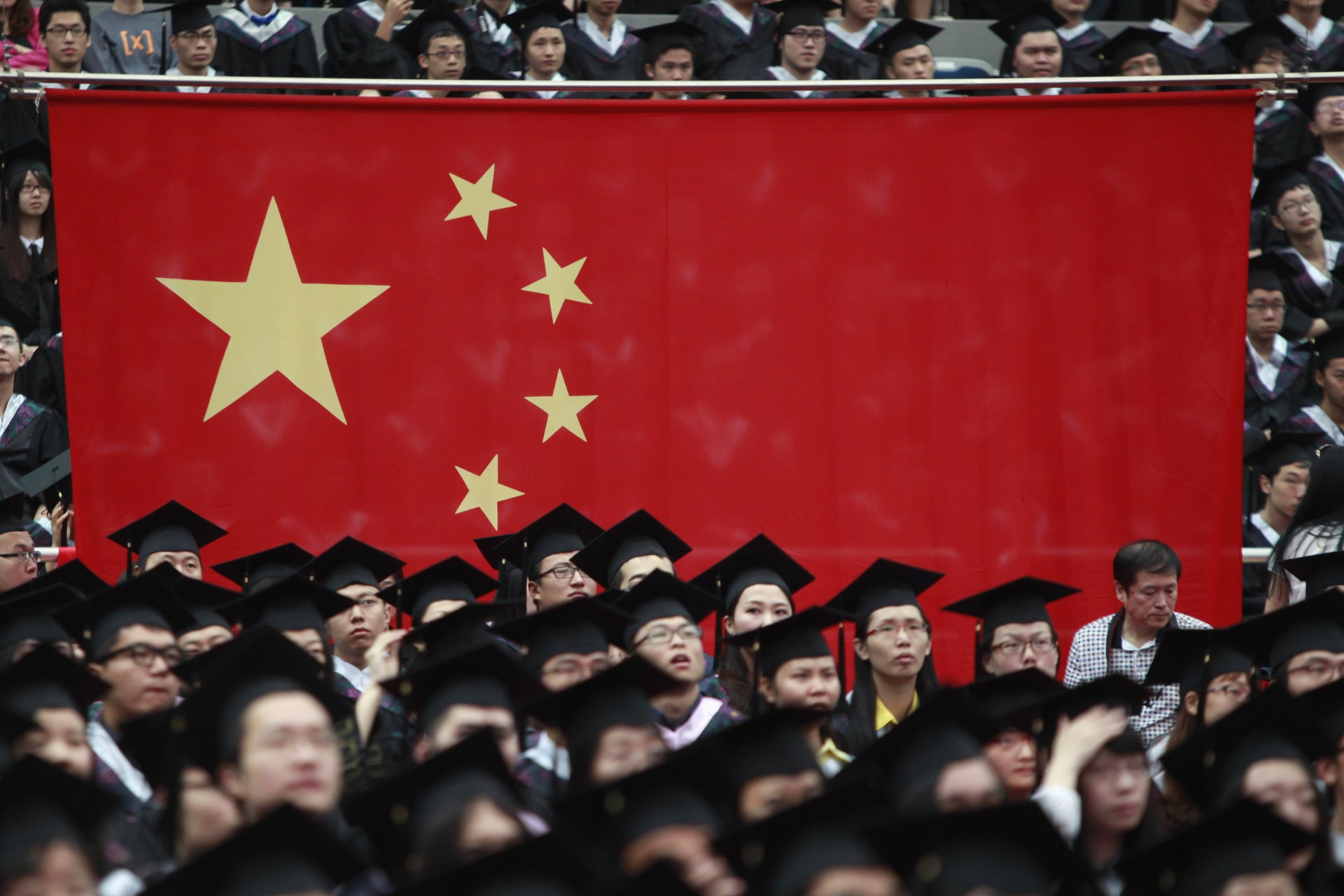 <p>Graduates set next to the Chinese flag during a graduation ceremony.</p>
