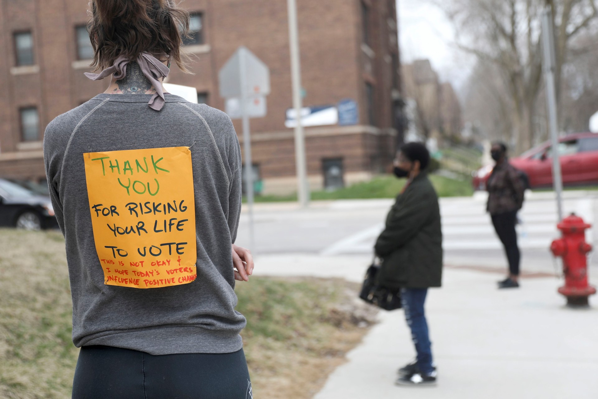 <p>Voter Rachel Messenger wears a sign reading “Thank you for risking your life to vote” as she waits in line outside Riverside University High School to cast a ballot during the presidential primary election held amid the coronavirus outbreak.</p>