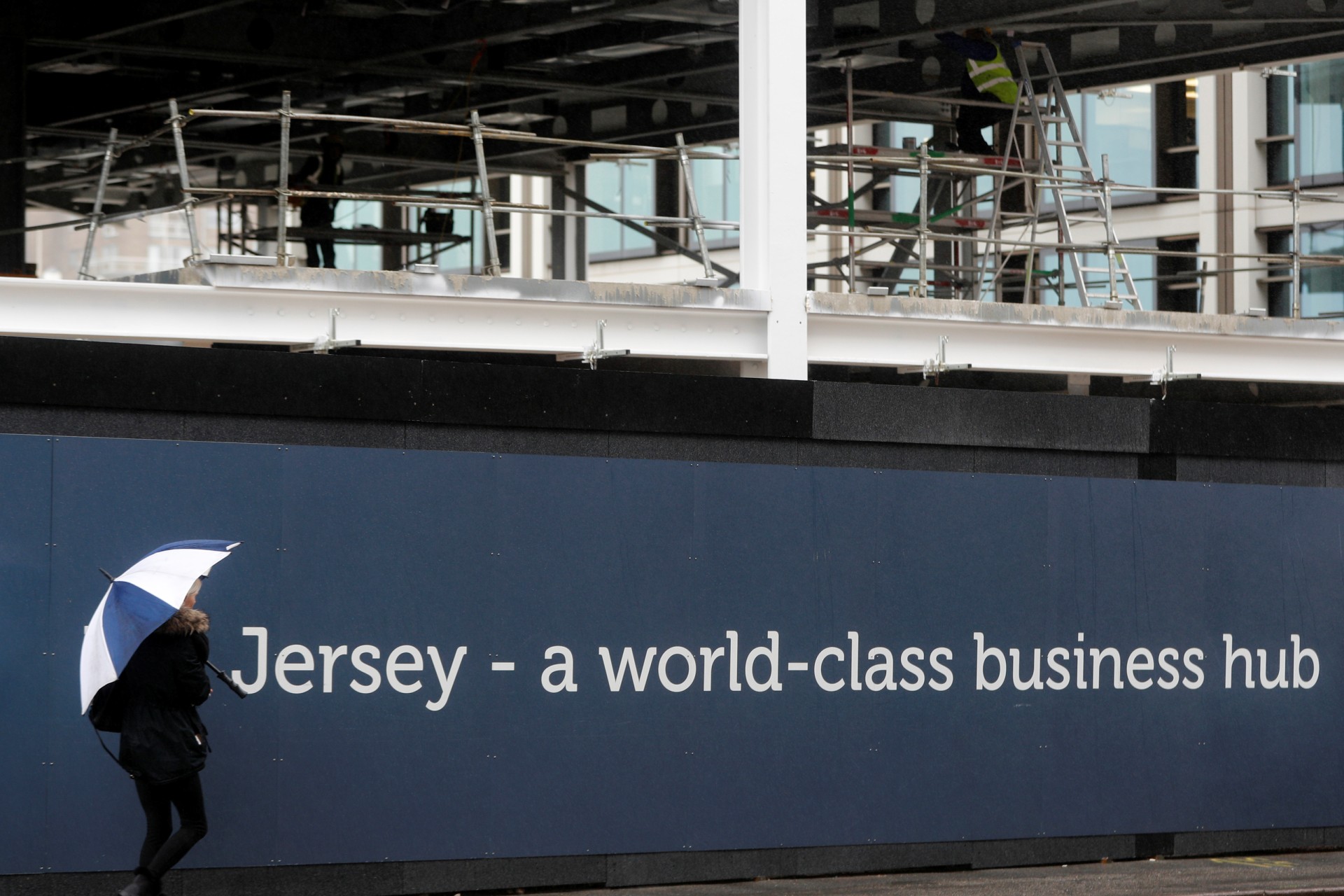 <p>A woman passes a new offices construction site in St Helier, Jersey, Britain, November 9, 2017.</p>