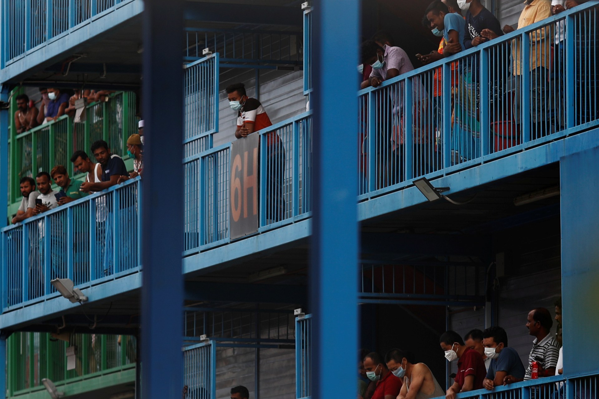 <p>Migrant workers look out from their balconies at Punggol S-11 dormitory, during the coronavirus outbreak in Singapore on April 6, 2020.</p>