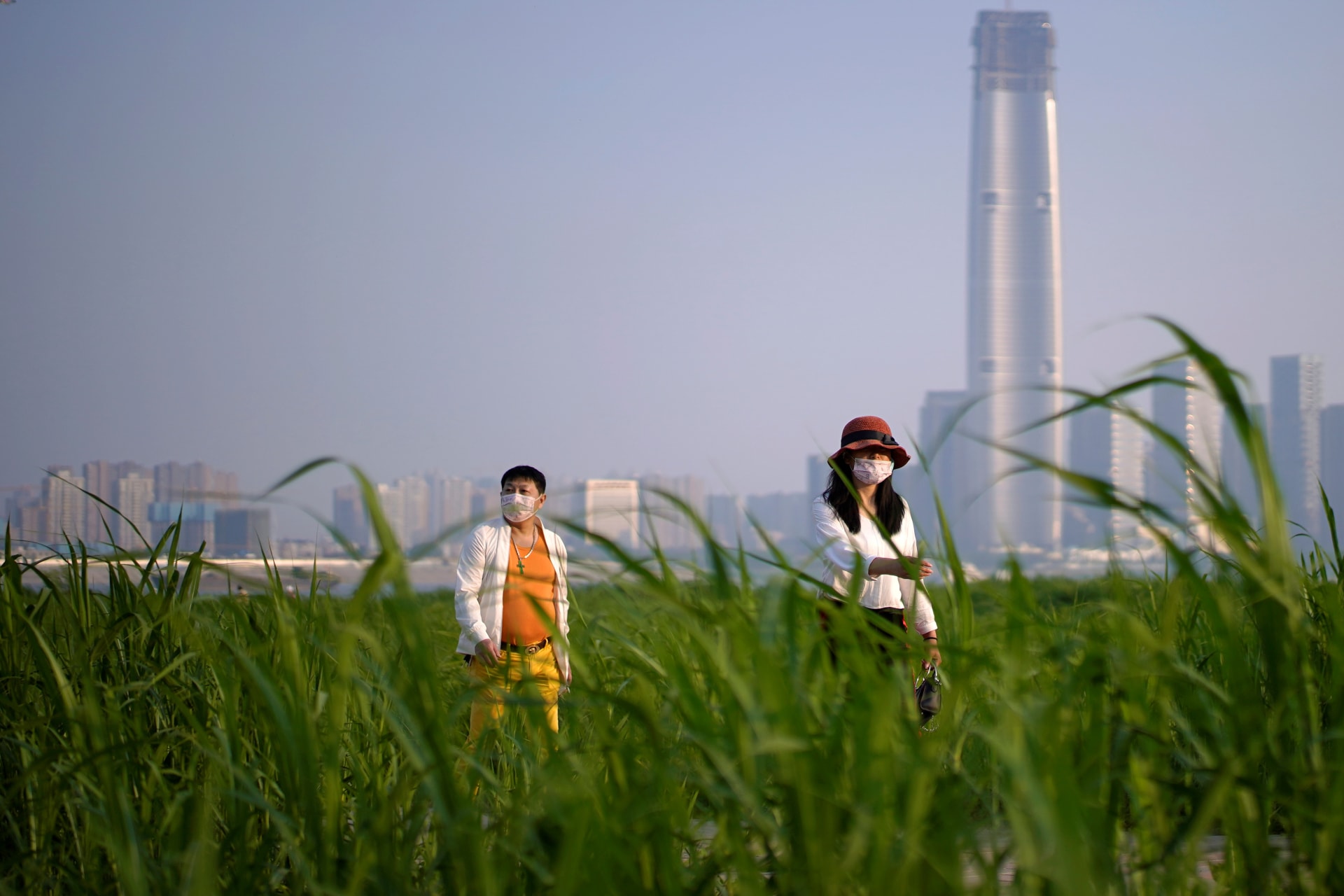 <p>People wearing face masks walk at a park in Wuhan, China, on April 12, 2020. </p>

