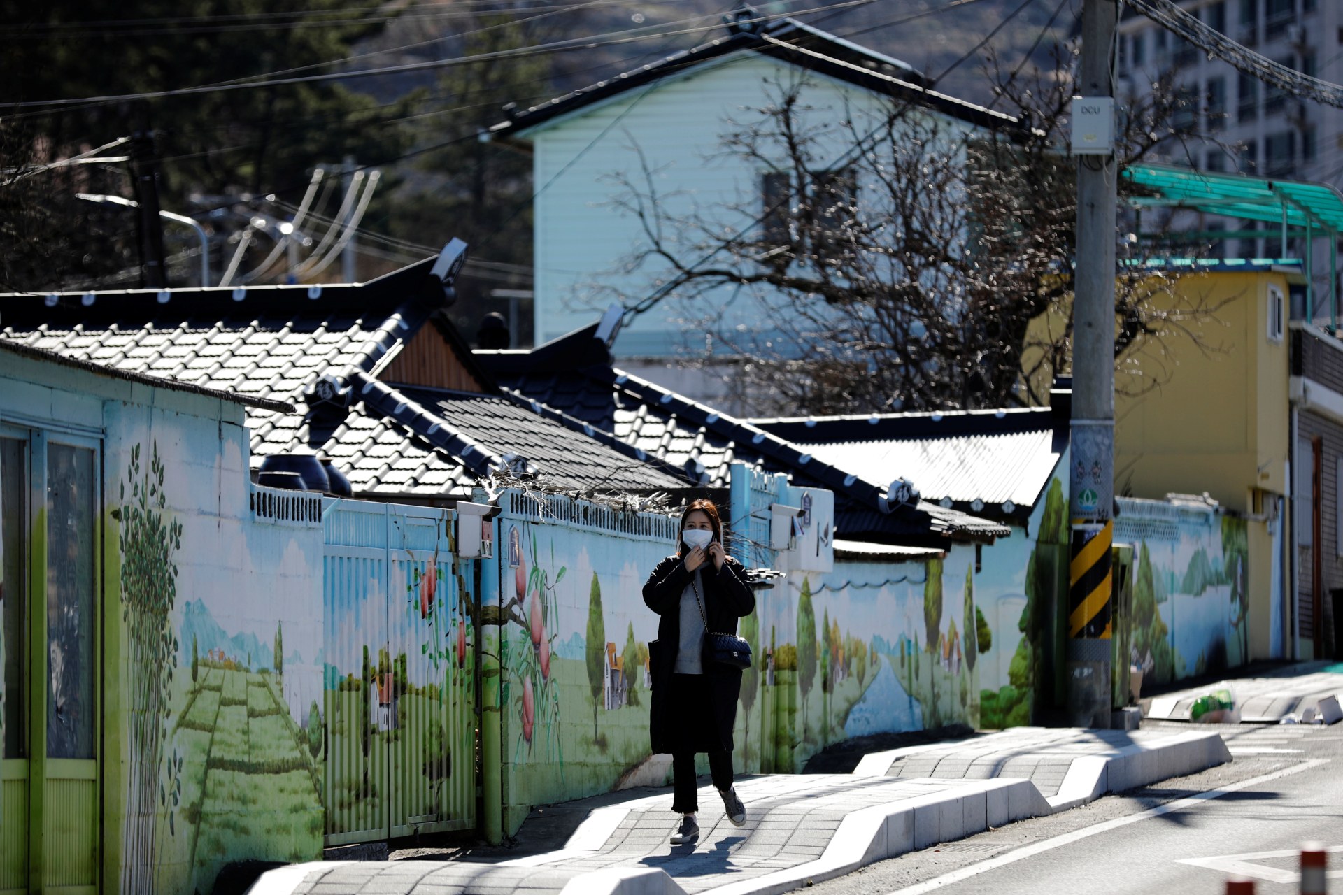 <p>A woman wearing a protective mask following an outbreak of COVID-19 walks through downtown Cheongdo County, near Daegu, South Korea, on March 11, 2020.</p>