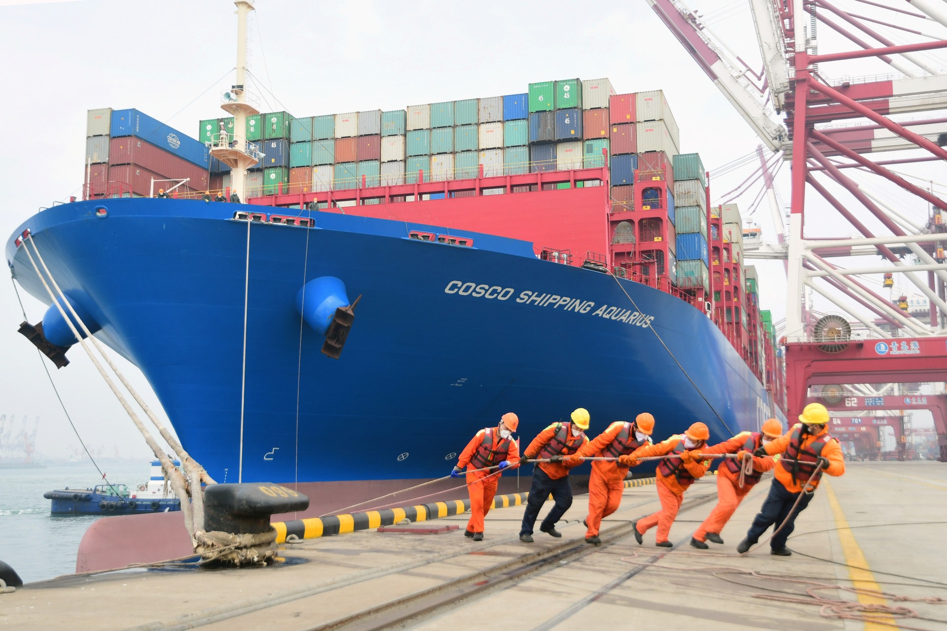 <p>Workers wearing face masks rope a container ship at a port in Qingdao, Shandong province, China February 11, 2020.</p>