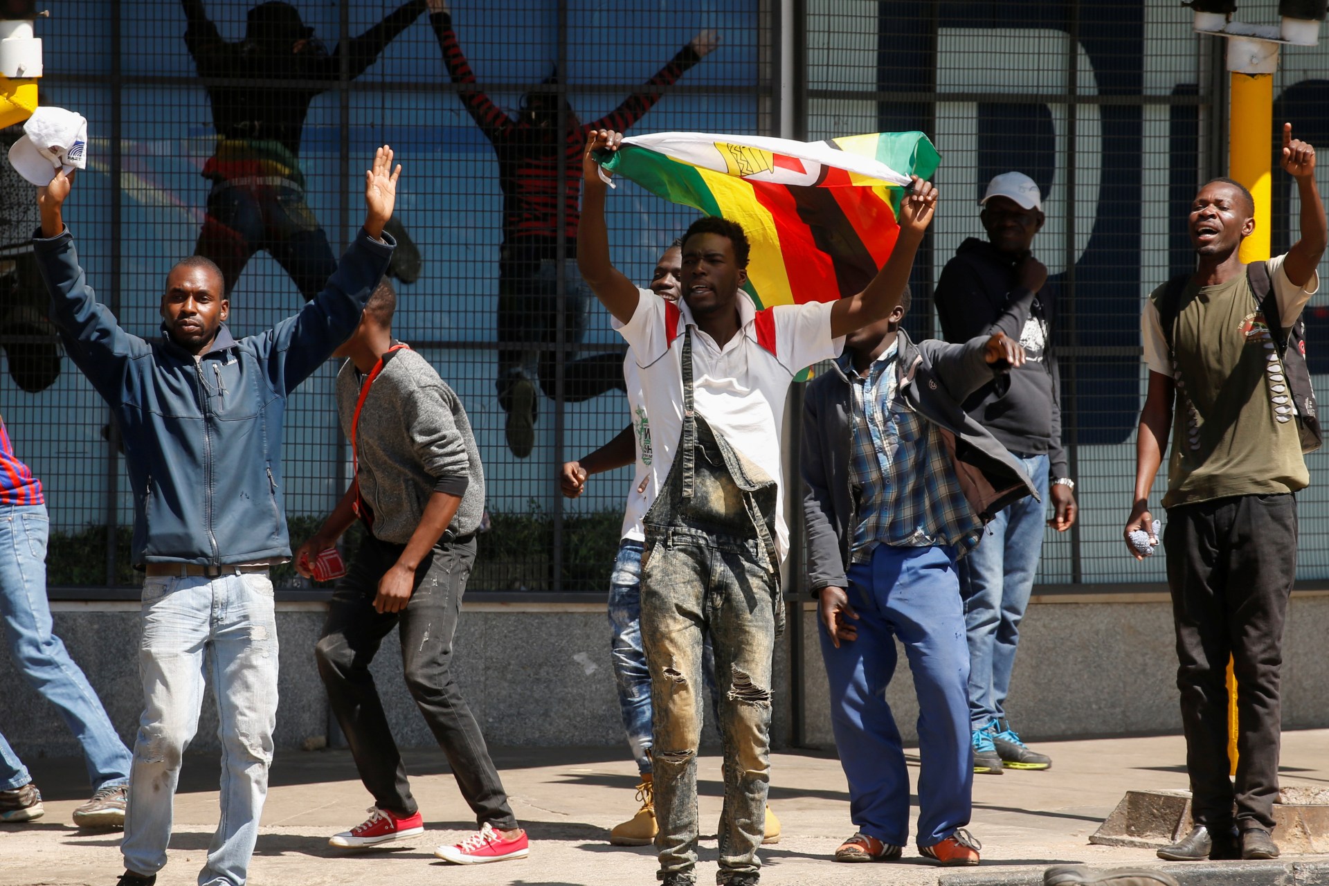 <p>Protesters hold flags during clashes after police banned planned protests over austerity and rising living costs called by the opposition Movement for Democratic Change (MDC) party in Harare, Zimbabwe, August 16, 2019</p>