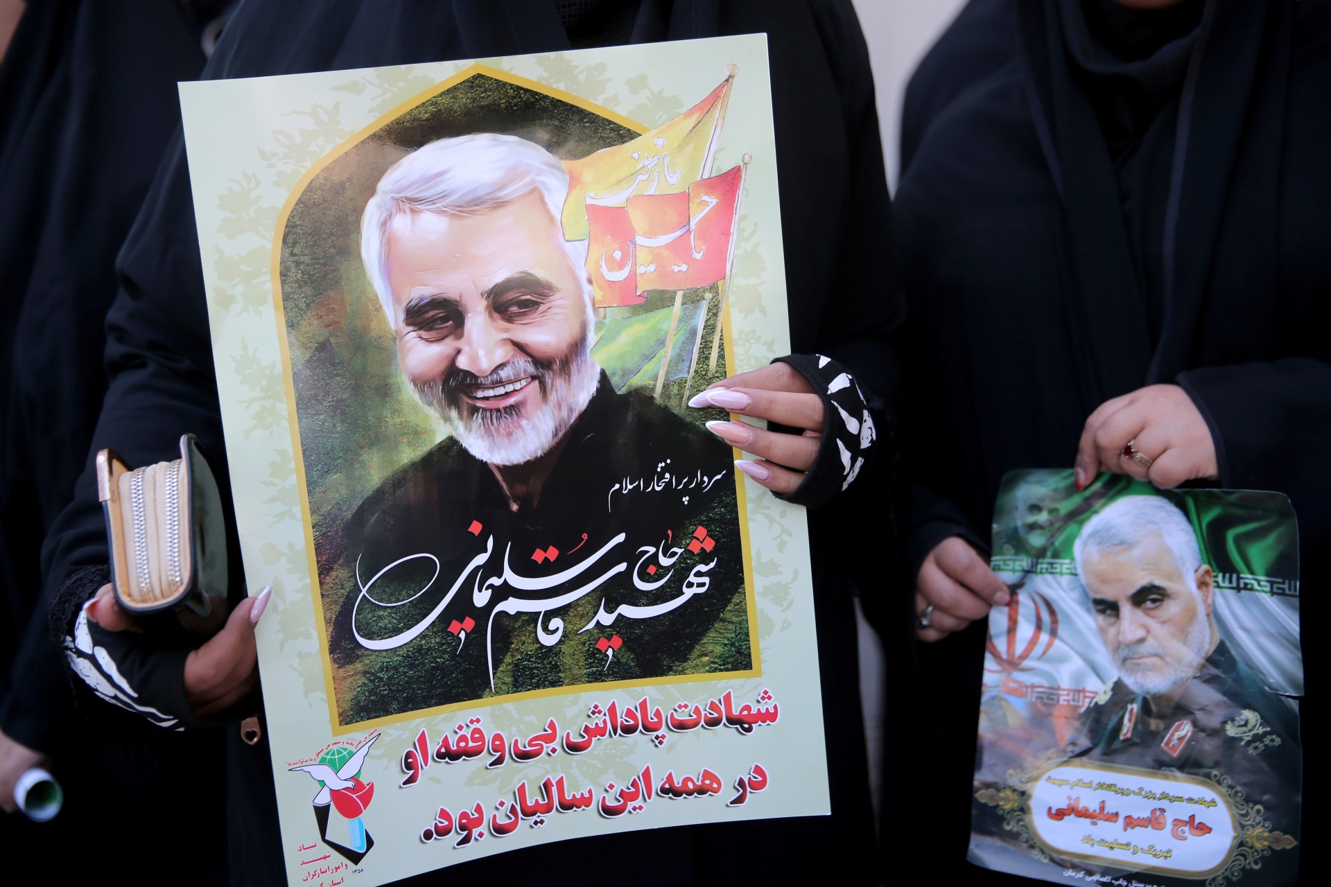 <p>Women hold pictures of Iranian Major-General Qassem Soleimani, head of the elite Quds Force, who was killed in an air strike at Baghdad airport, during a funeral procession and burial at his hometown in Kerman, Iran, on January 7, 2020.</p>