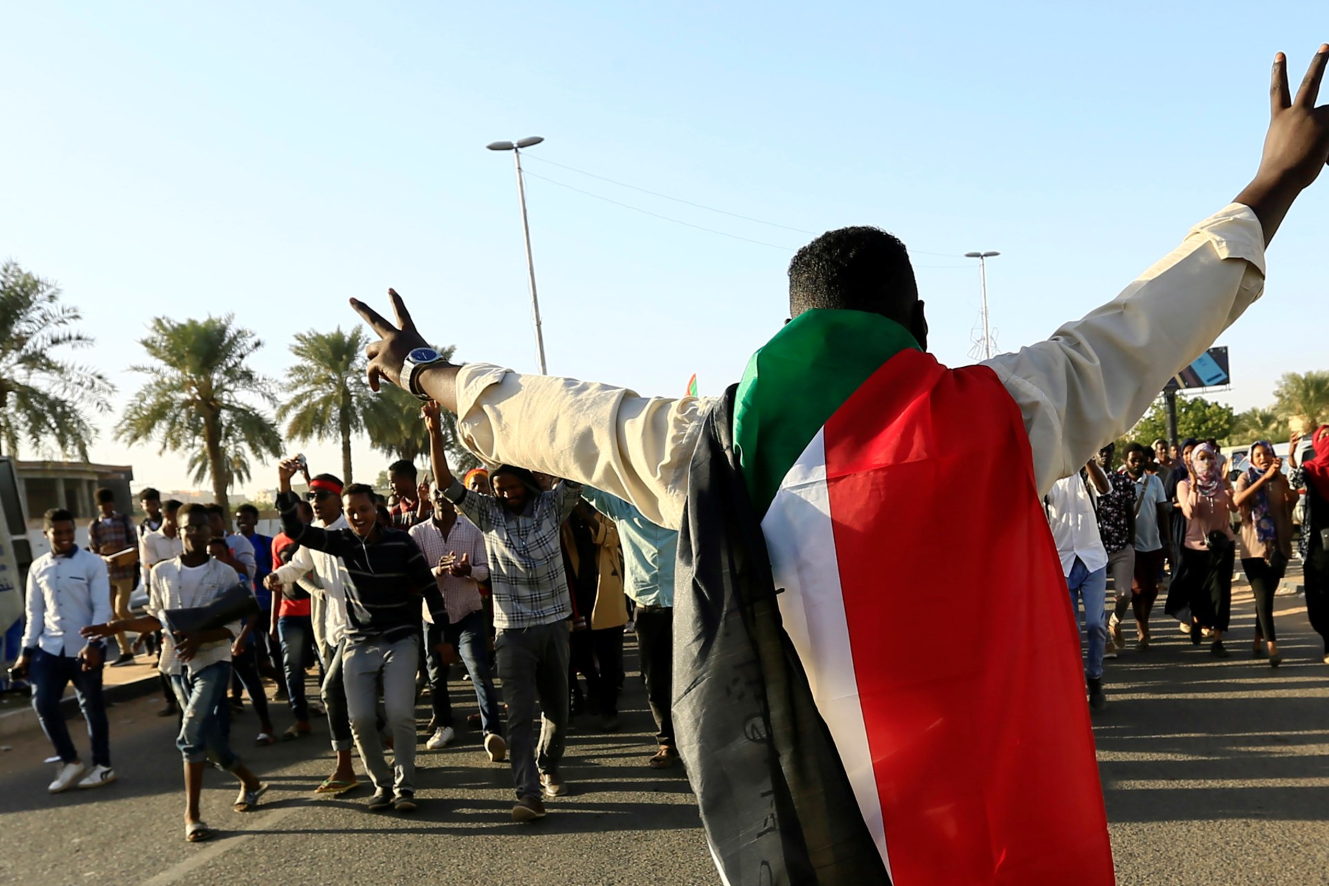 <p>A Sudanese man wears a national flag and flashes the victory sign as people gather during the first anniversary of the start of the uprising that toppled long-time ruler Omar al-Bashir, in Khartoum, Sudan December 19, 2019</p>
