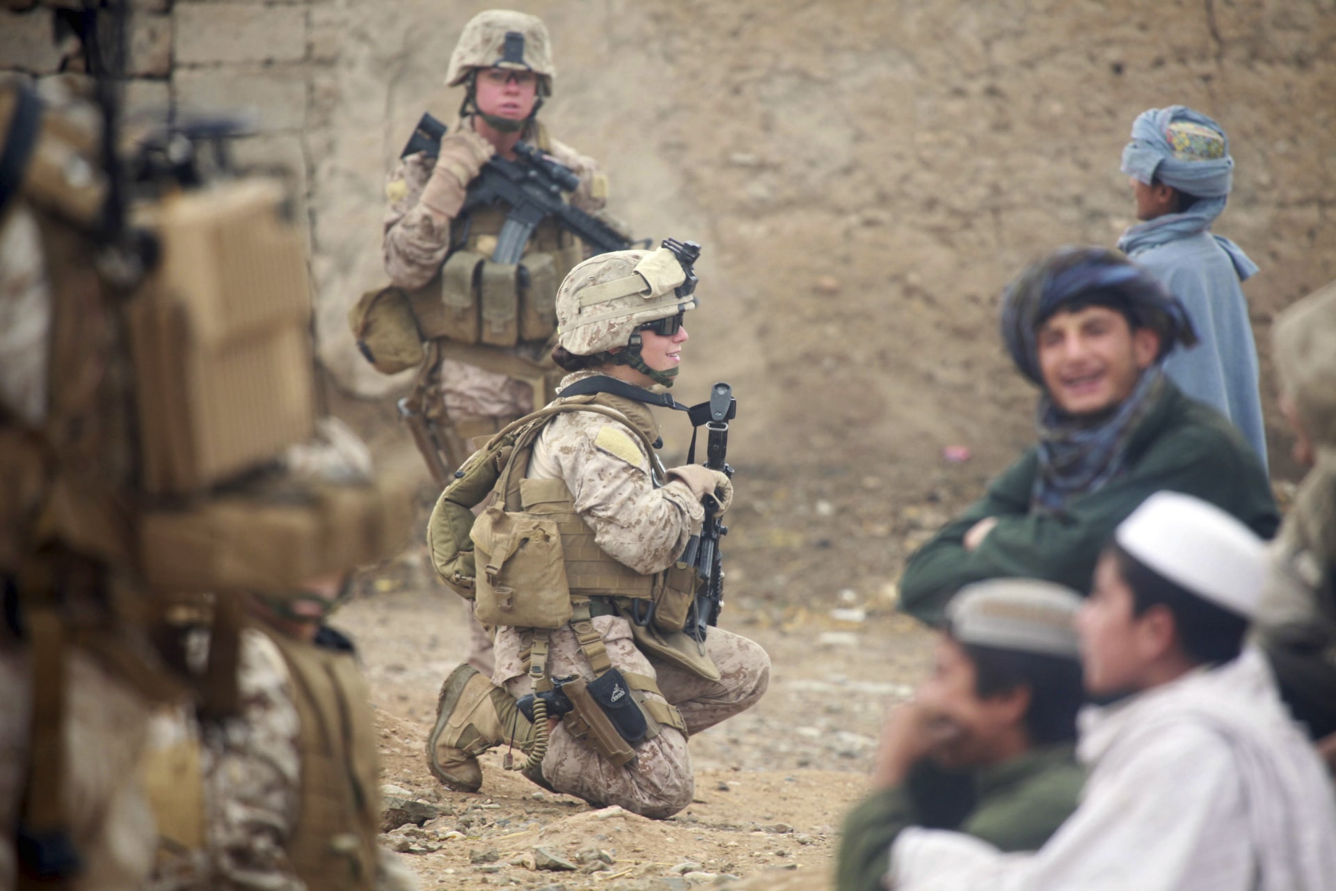 <p>U.S. Marine Corps Lance Cpl. Sienna De Santis and U.S. Navy Petty Officer 3rd Class Heidi Dean, both with Female Engagement Team, greet children during a patrol in Sangin Valley, Afghanistan, 2010.</p>