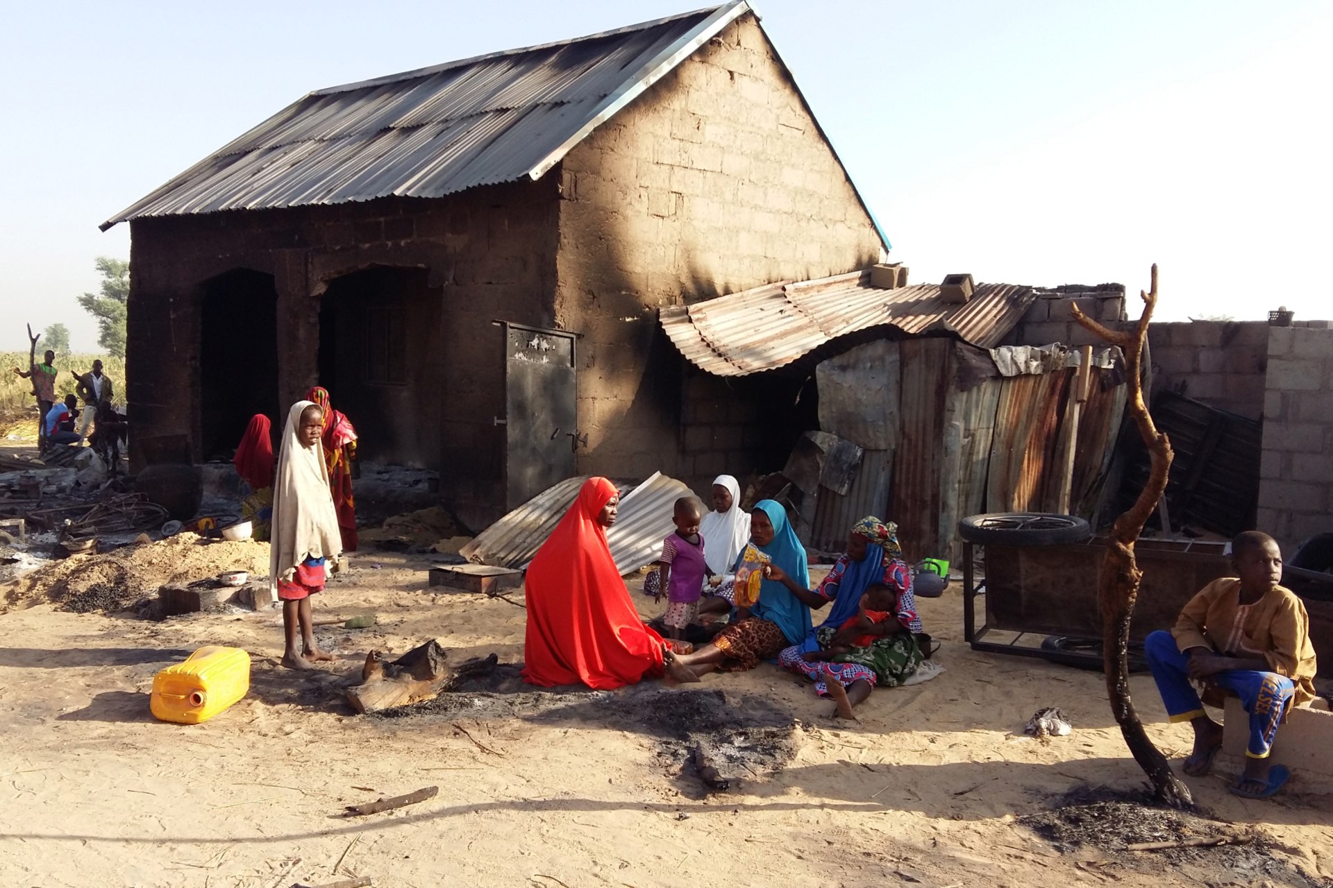 <p>People sit near a burnt house after an attack by suspected members of the Islamist Boko Haram insurgency in Bulabulin village, Nigeria, on November 1, 2018.</p>
