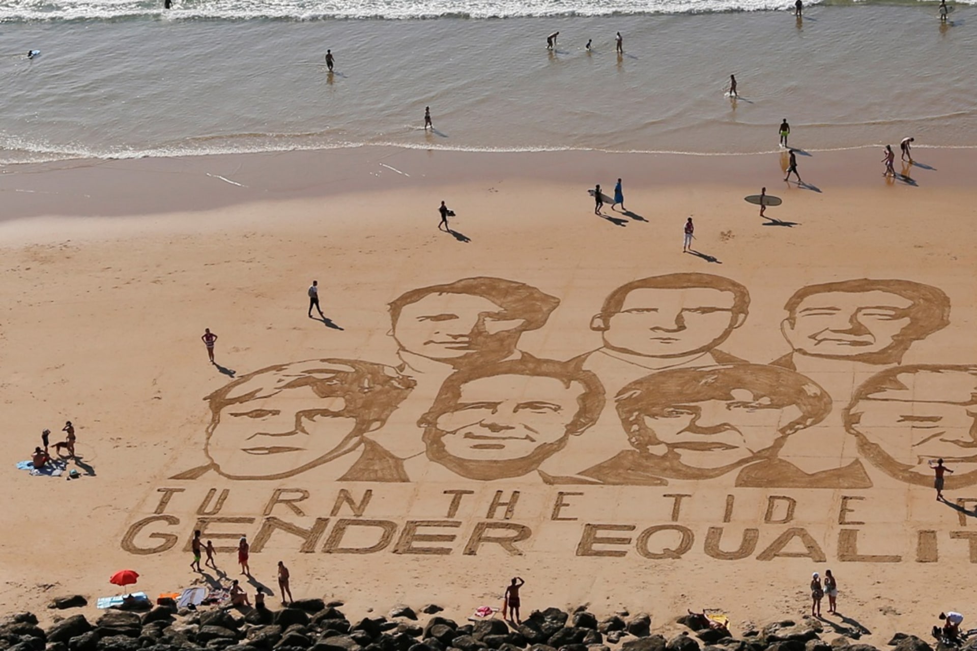 <p>The faces of the G7 leaders are drawn in sand with the message “Turn the Tide for Gender Equality.”</p>
