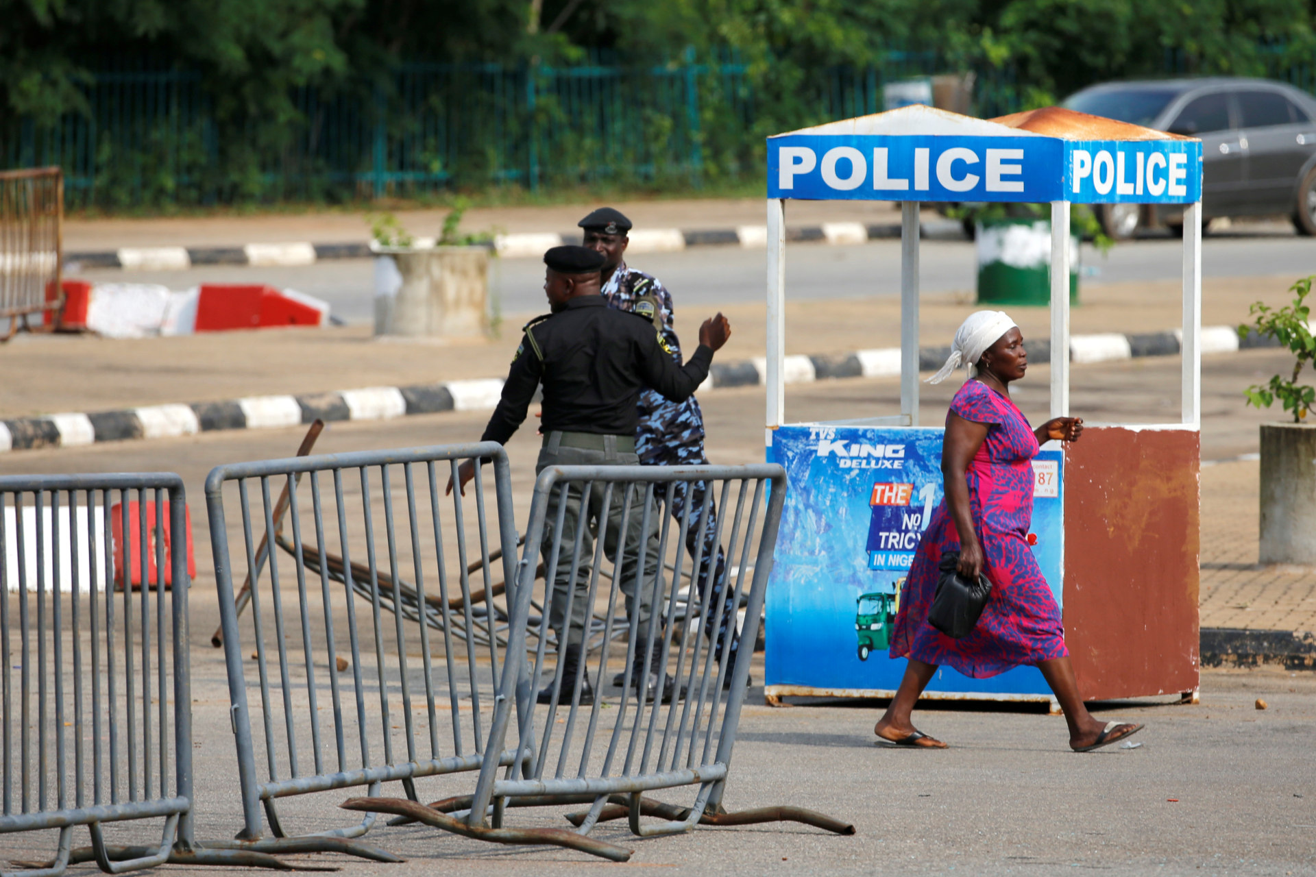 <p>A woman walks past police officers outside the National Assembly, after clashes between police and a group of Shiite protesters in Abuja, Nigeria, on July 9, 2019.</p>